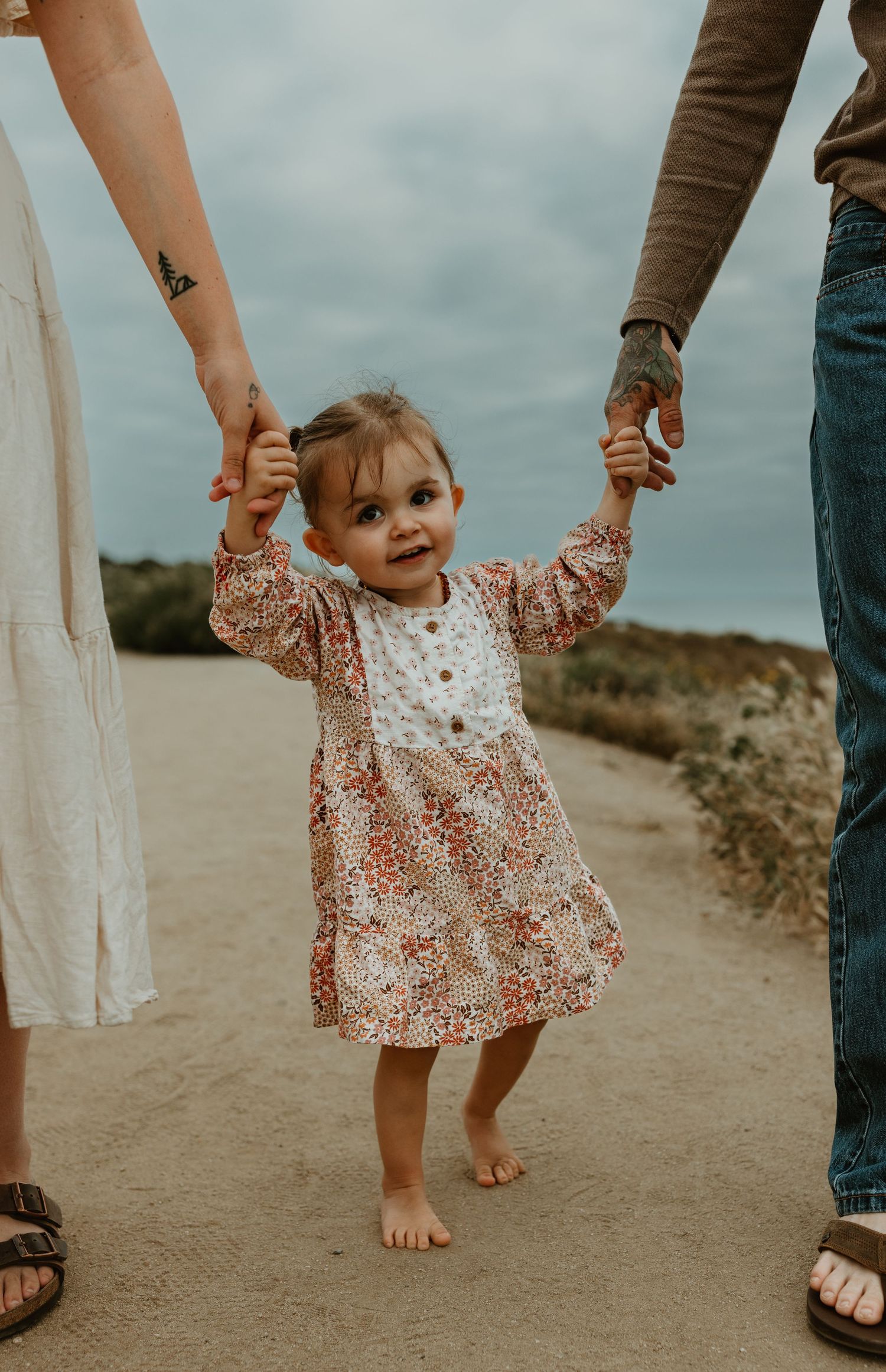 baby holding hands with parents at sunset cliffs