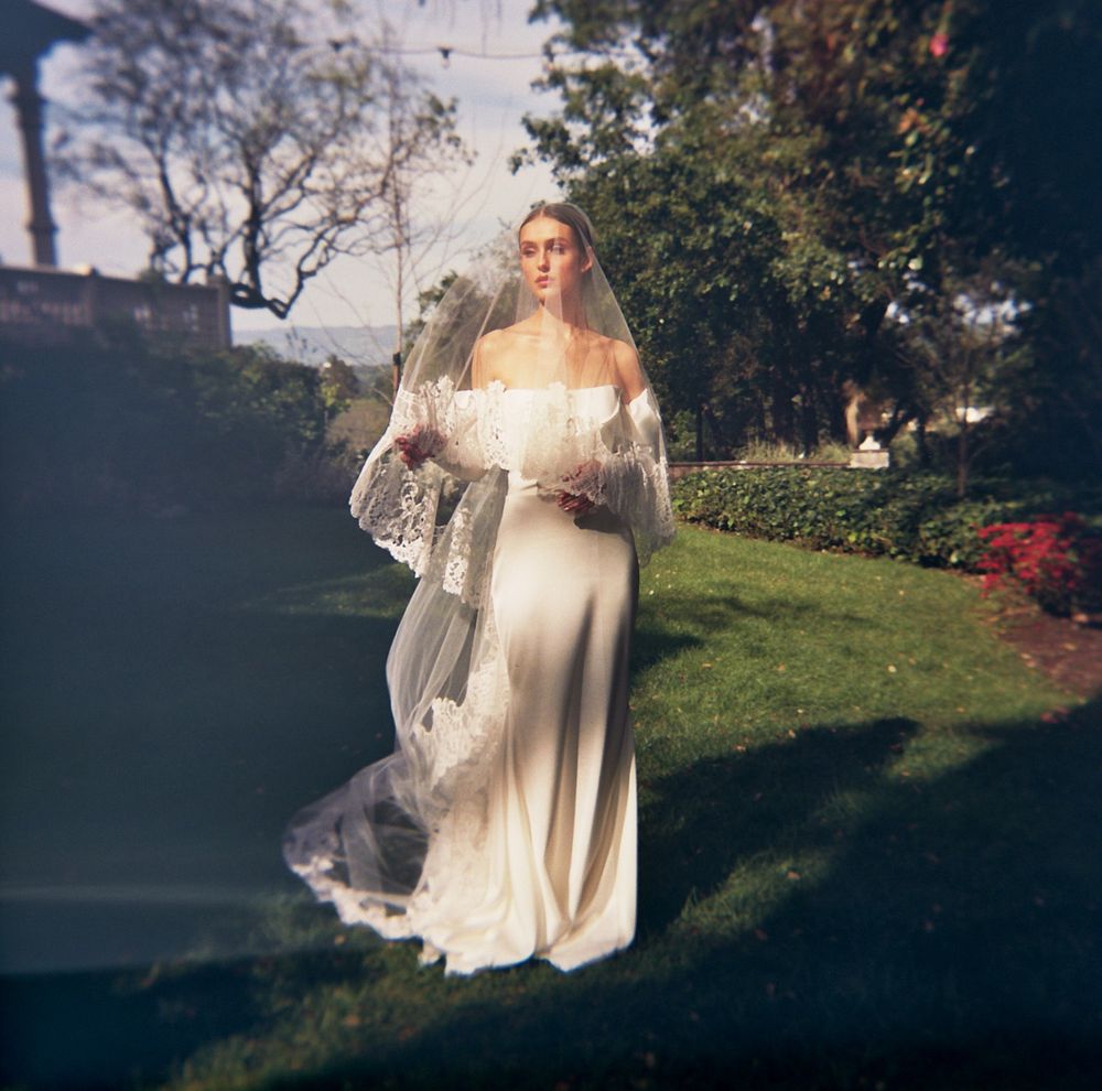Ethereal sunlit scene with flowing white dress against garden backdrop captured on film by Danielle Conner Photography.