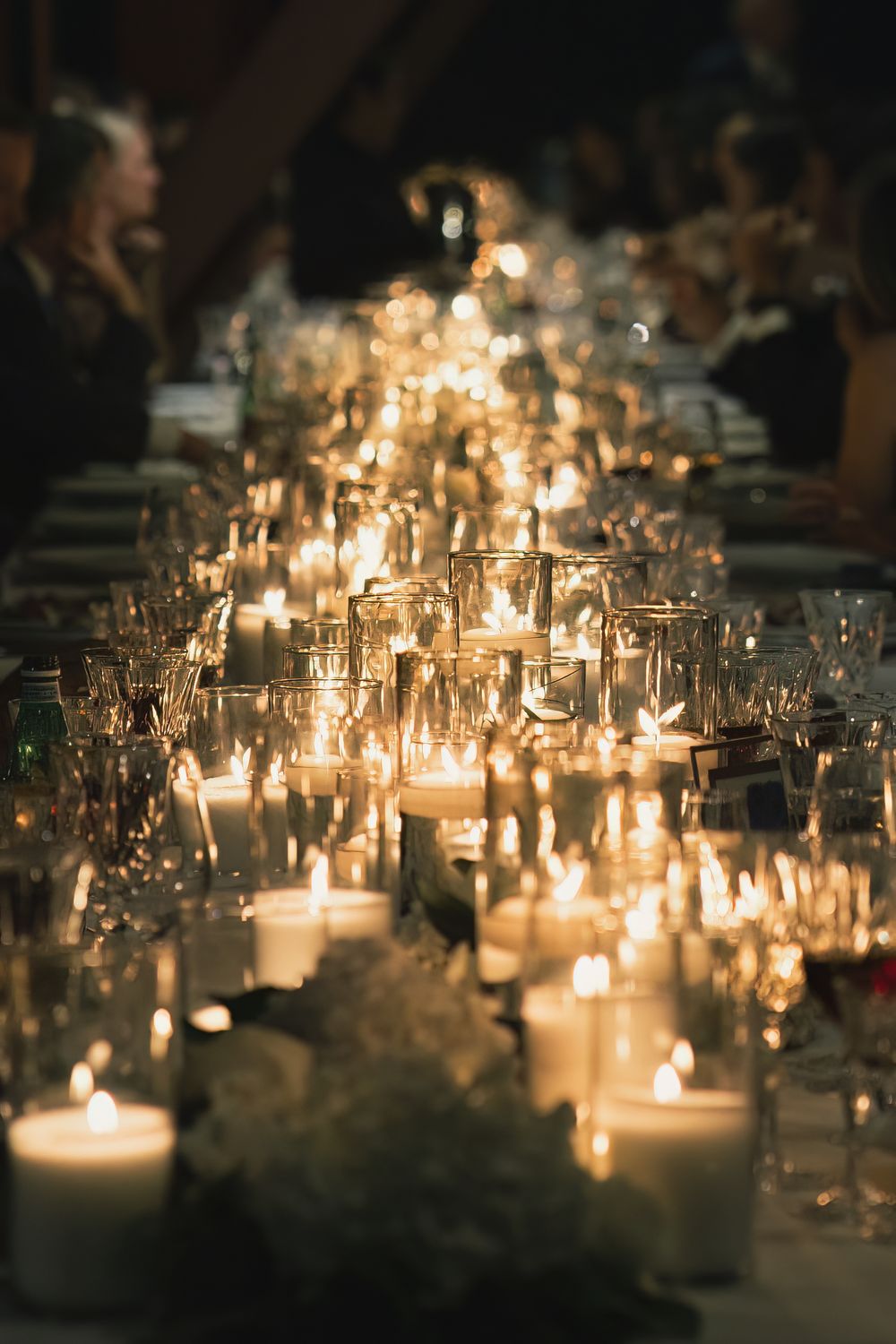 Romantic candlelit table setting with multiple glass votives creating ambient glow.