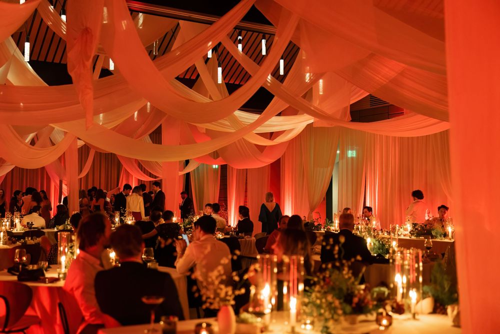 Elegant reception hall decorated with white fabric and red uplighting creating a romantic atmosphere.