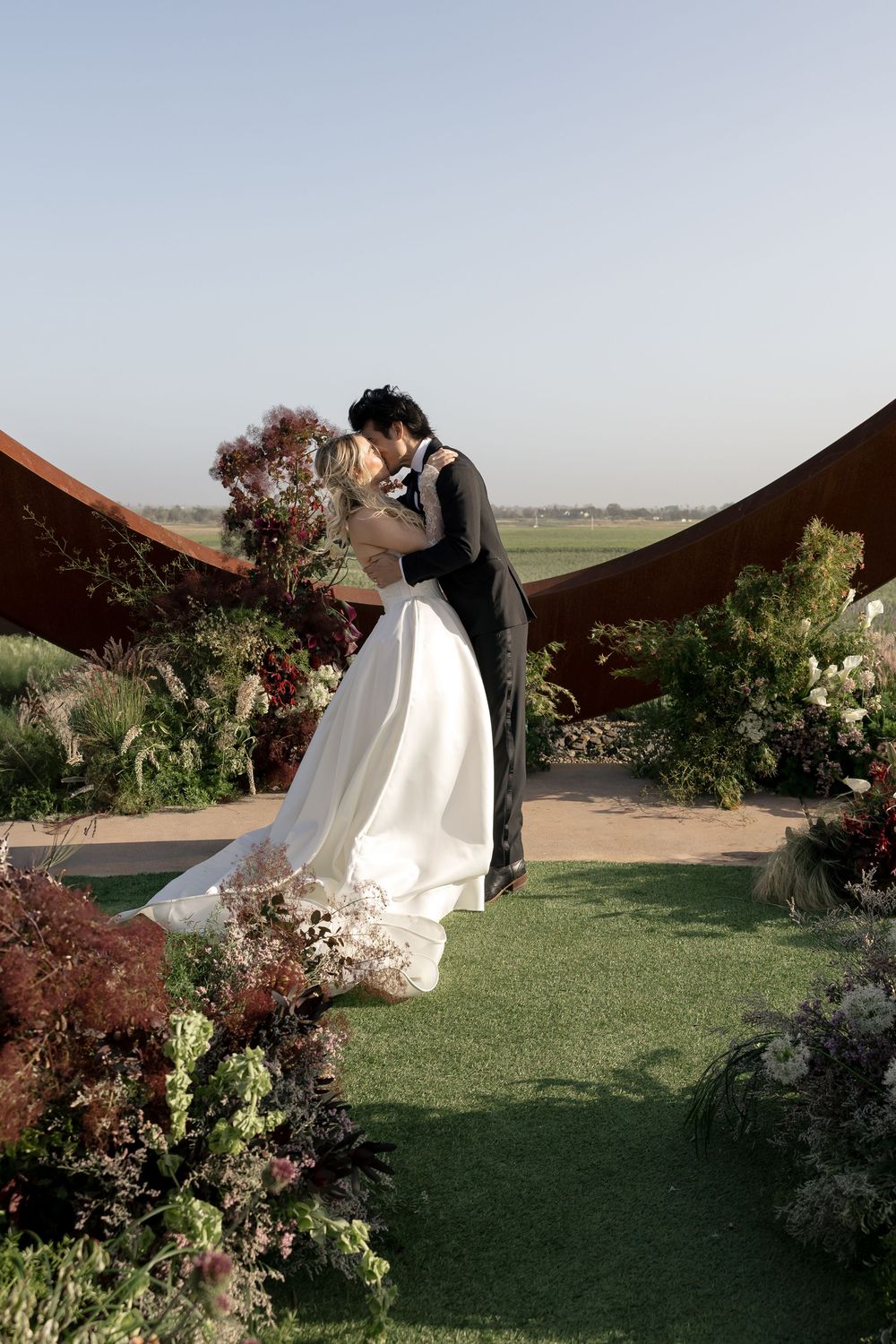 A romantic wedding moment captured between newlyweds surrounded by floral arrangements.