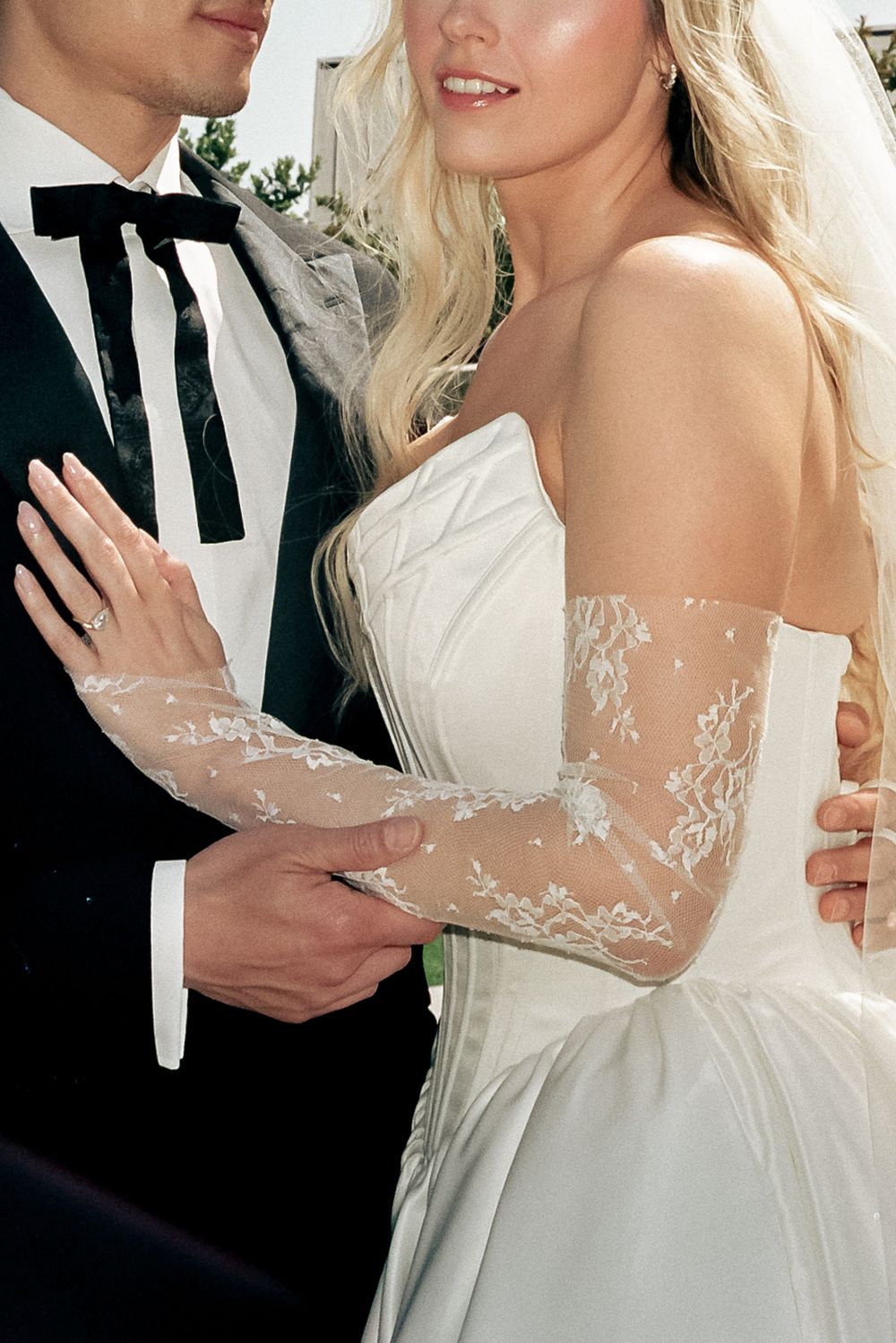 Close-up details of delicate lace sleeves on a white wedding gown with sheer fabric.