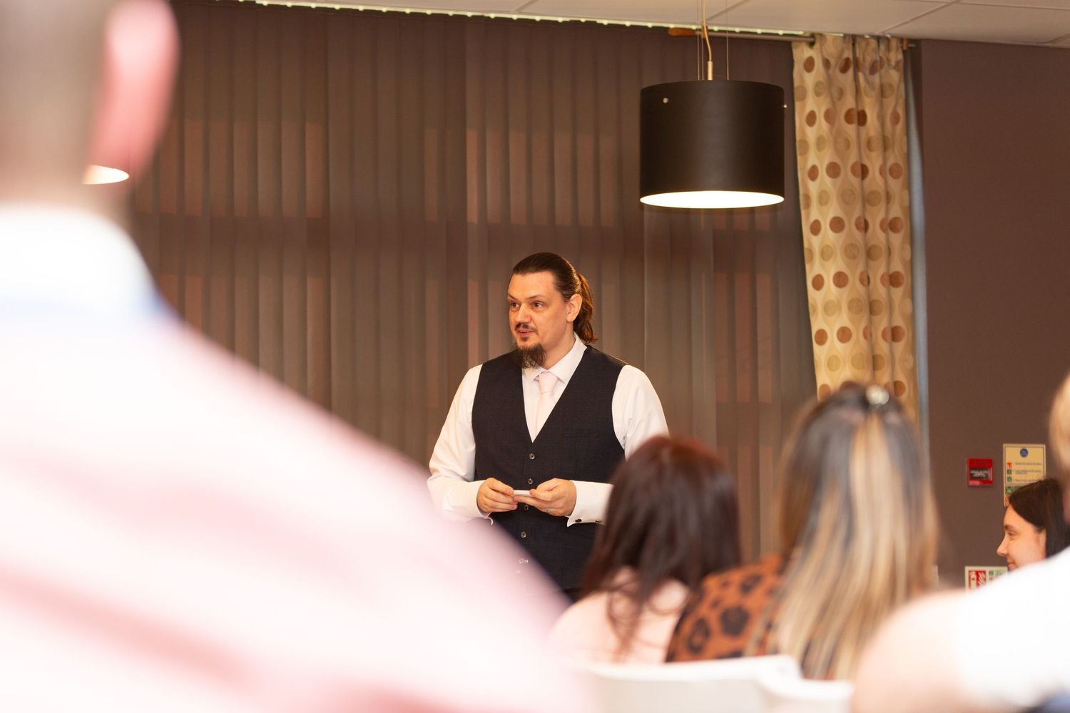 Server in formal attire addresses guests during an elegant indoor reception event.
