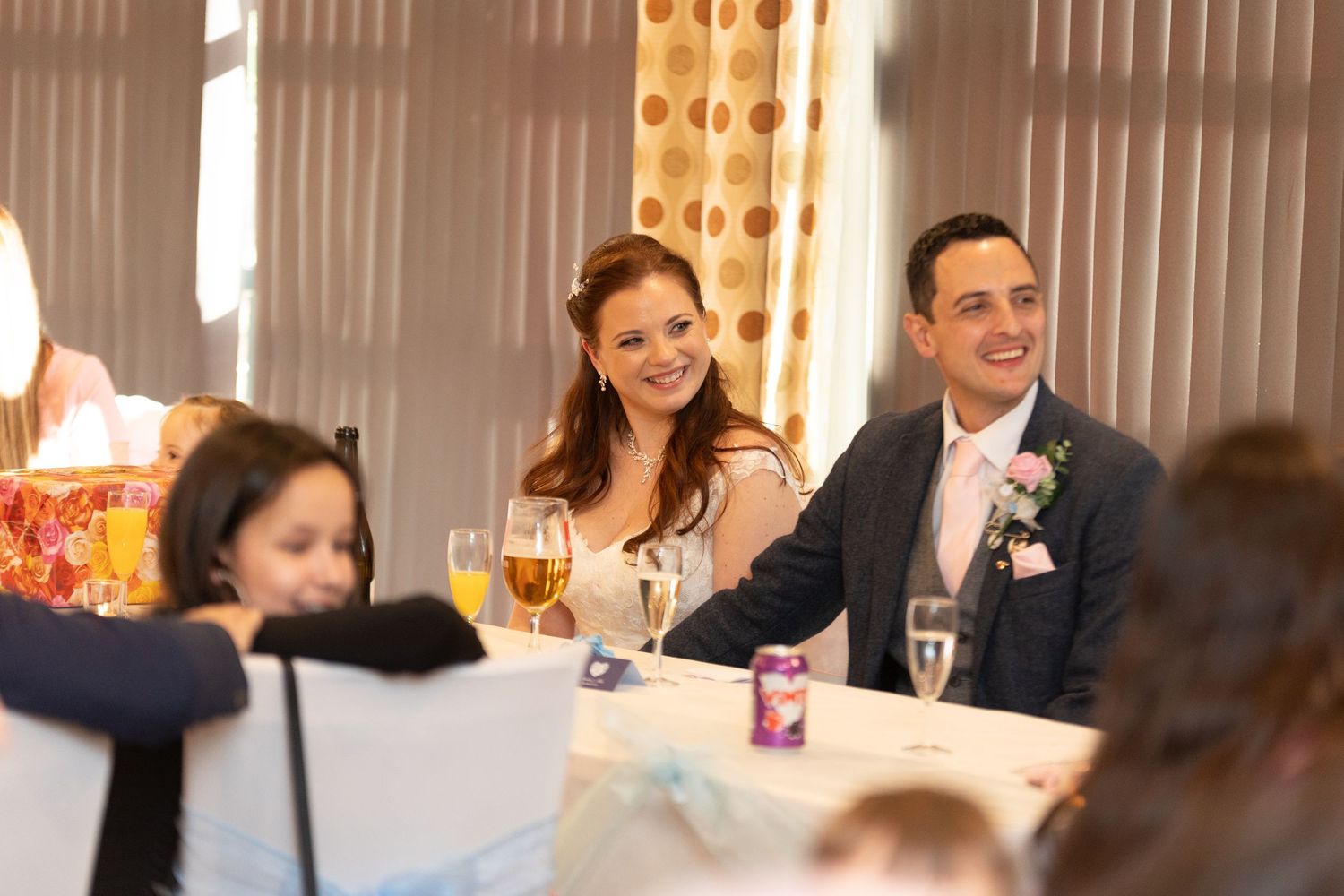 Wedding reception guests seated at decorated tables enjoying celebratory drinks.