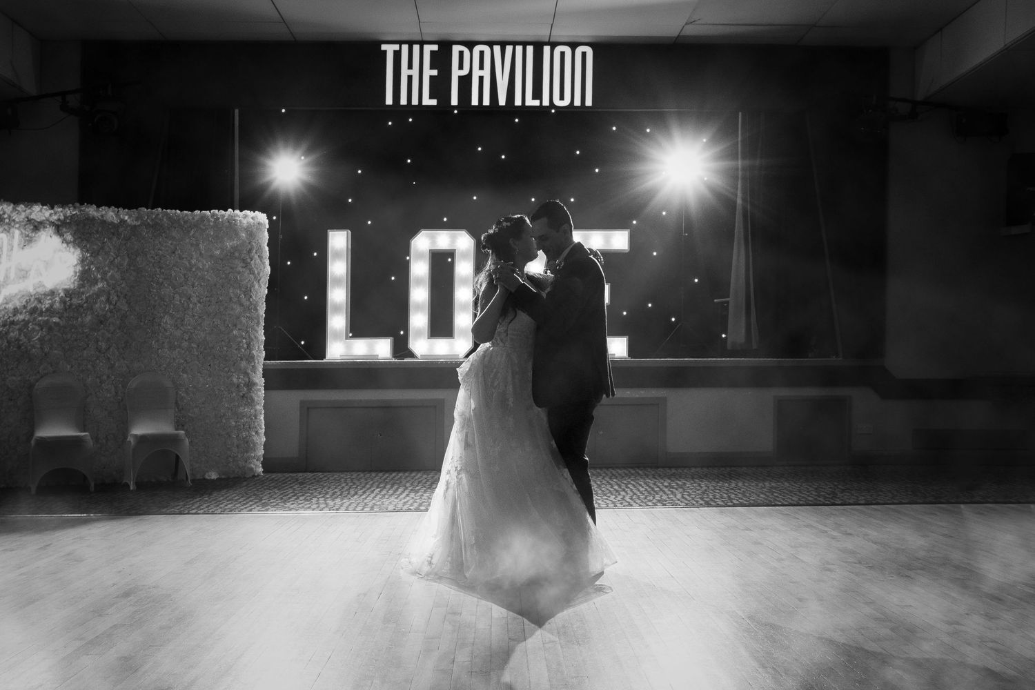 Romantic silhouette of couple dancing under illuminated 'The Pavilion' sign.