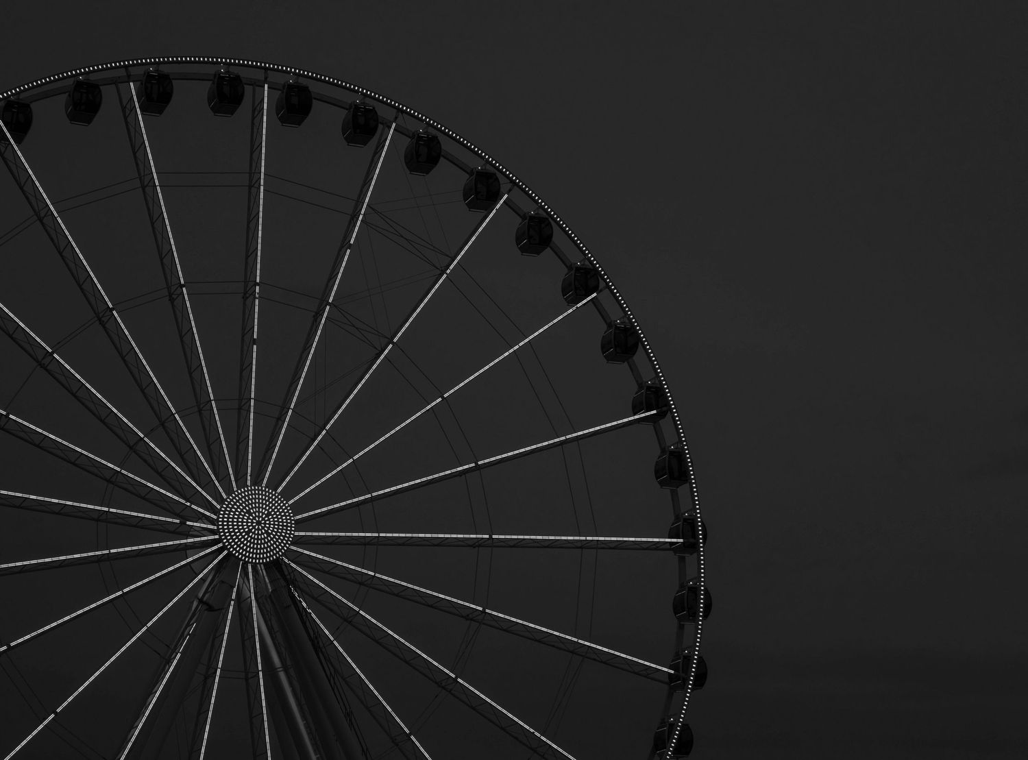 Black and white silhouette of a Ferris wheel against a dark background.