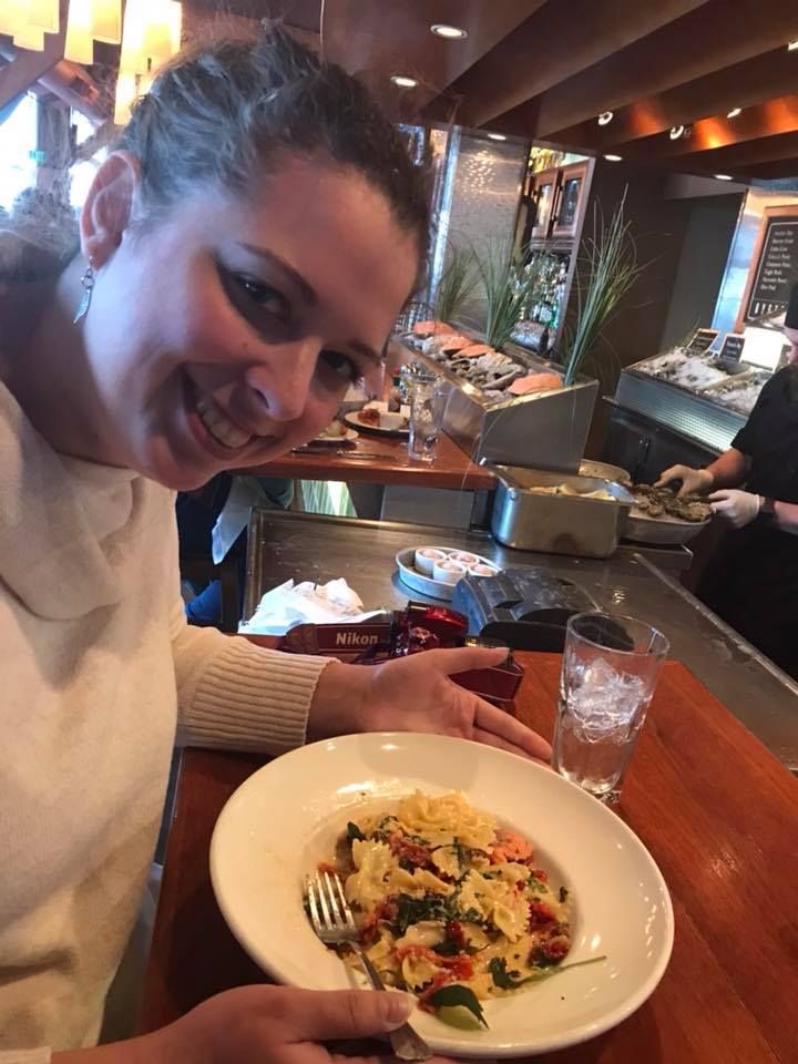 Fresh pasta dish served on white plate at restaurant bar.