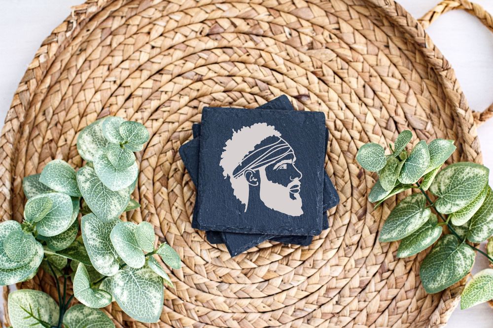 Profile silhouette design on navy card positioned on woven placemat with green leaves.
