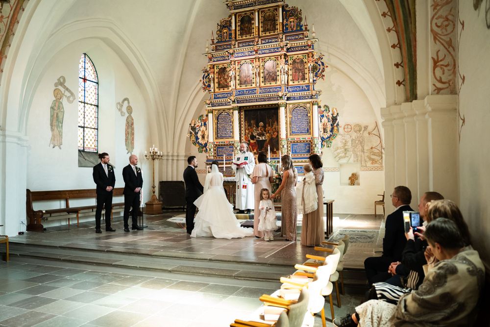 Wedding ceremony inside a historic church with ornate golden altar.