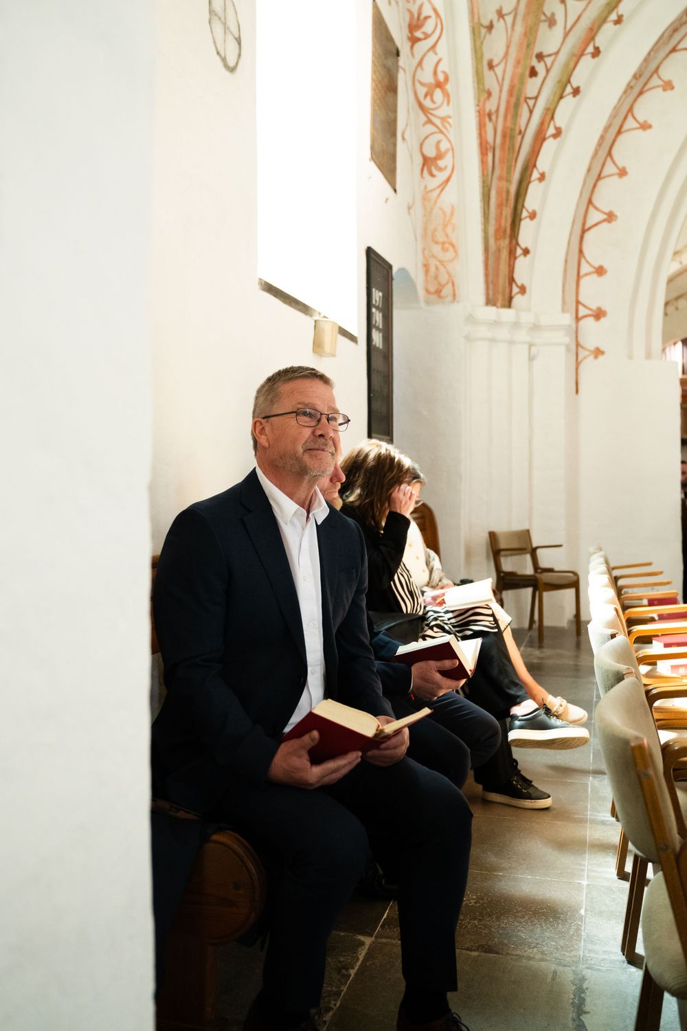 Church interior with guests reading from hymnals during a service.