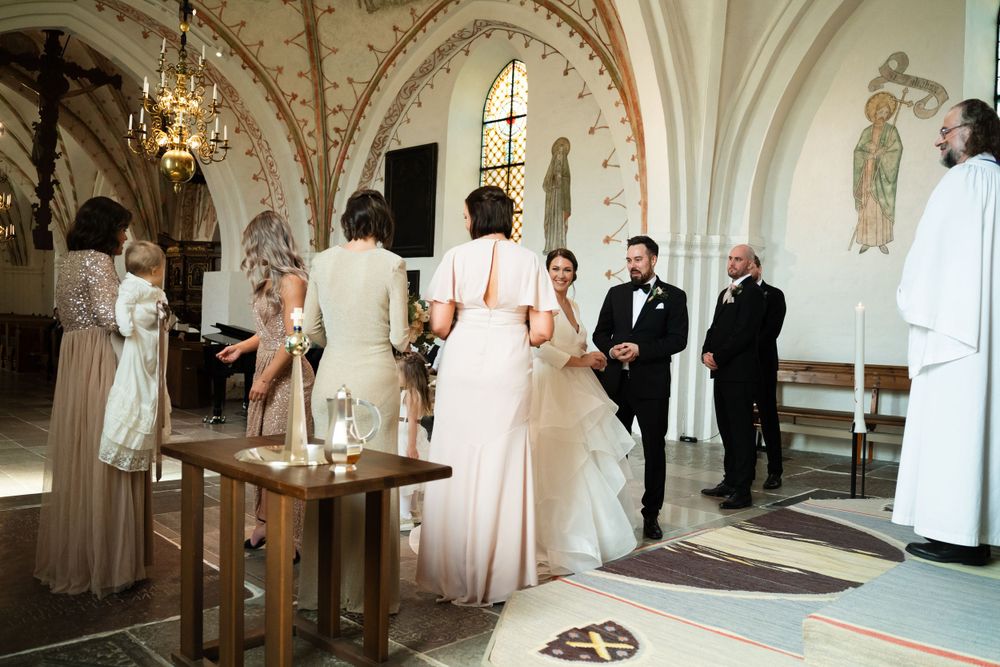 Wedding ceremony in ornate church with decorative arches and chandelier.
