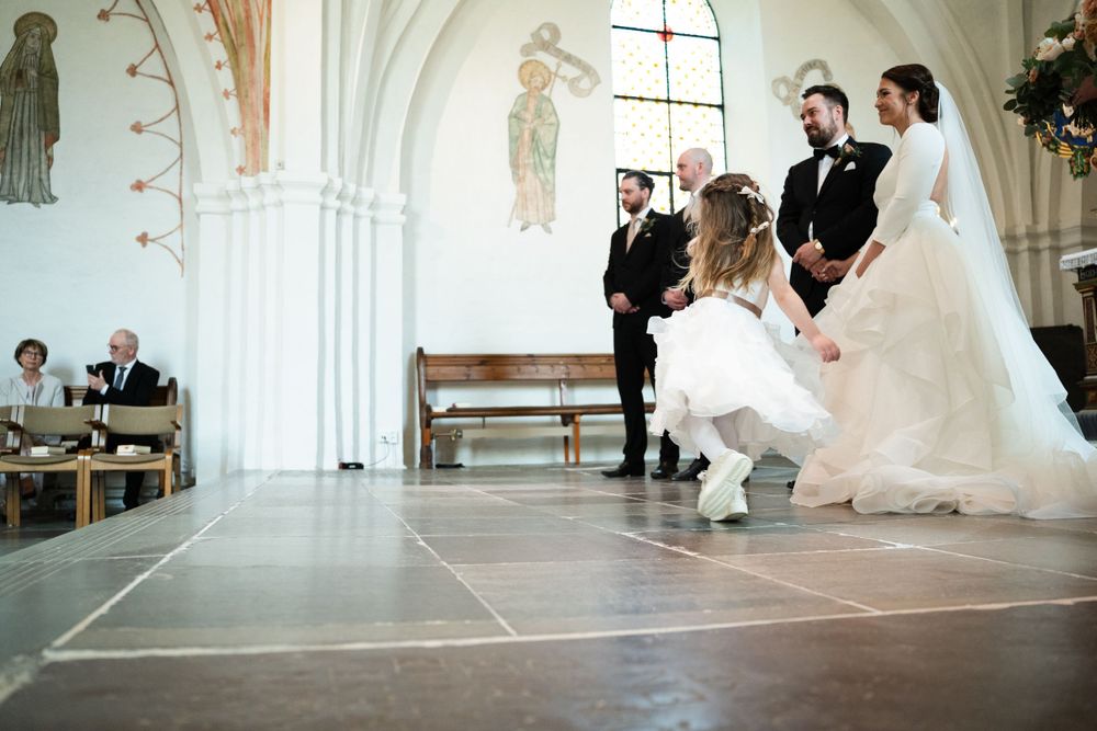 Wedding ceremony in historic church with white walls and decorative murals.