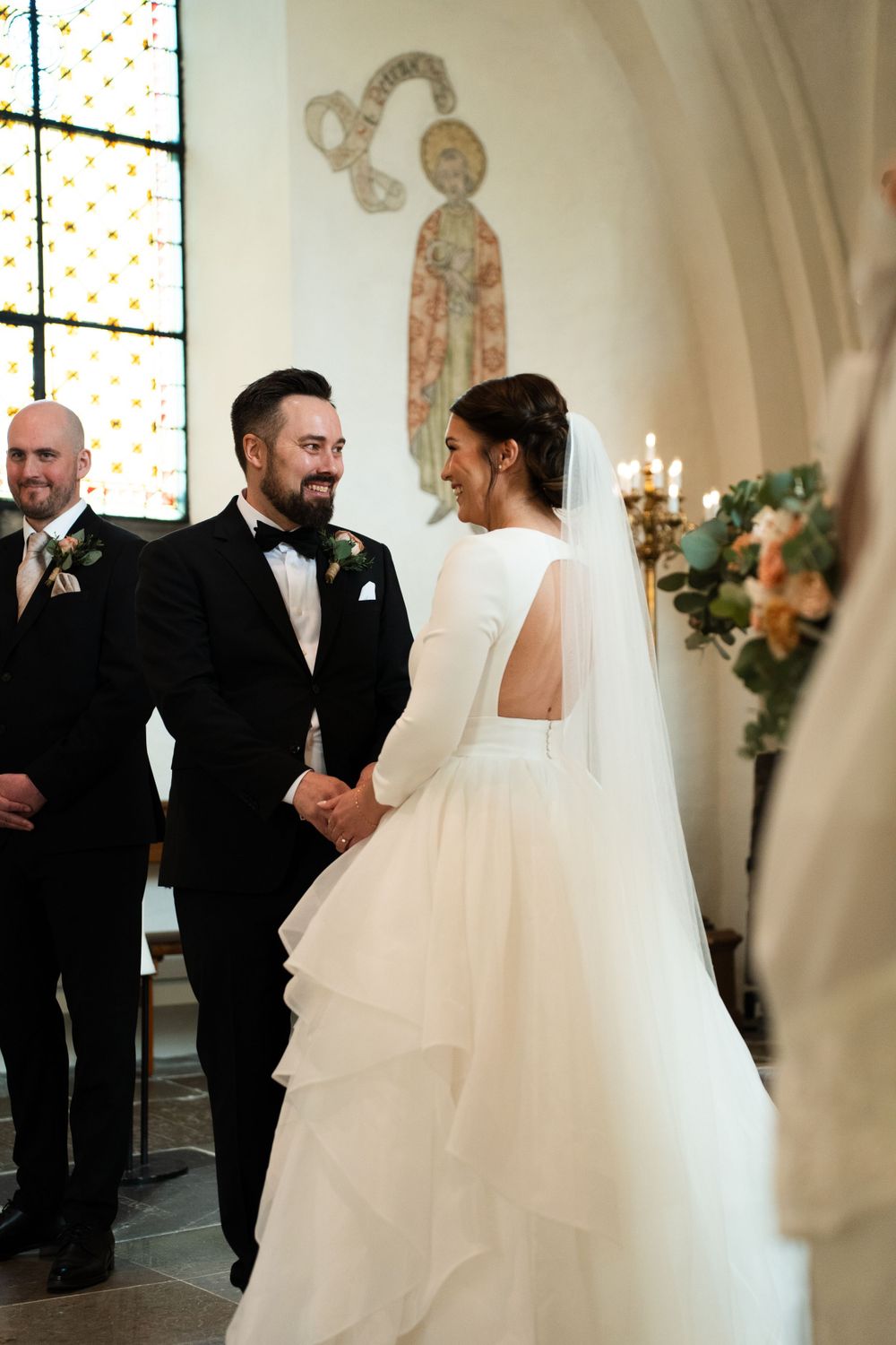 Elegant wedding ceremony in church with stained glass windows and ornate architecture.