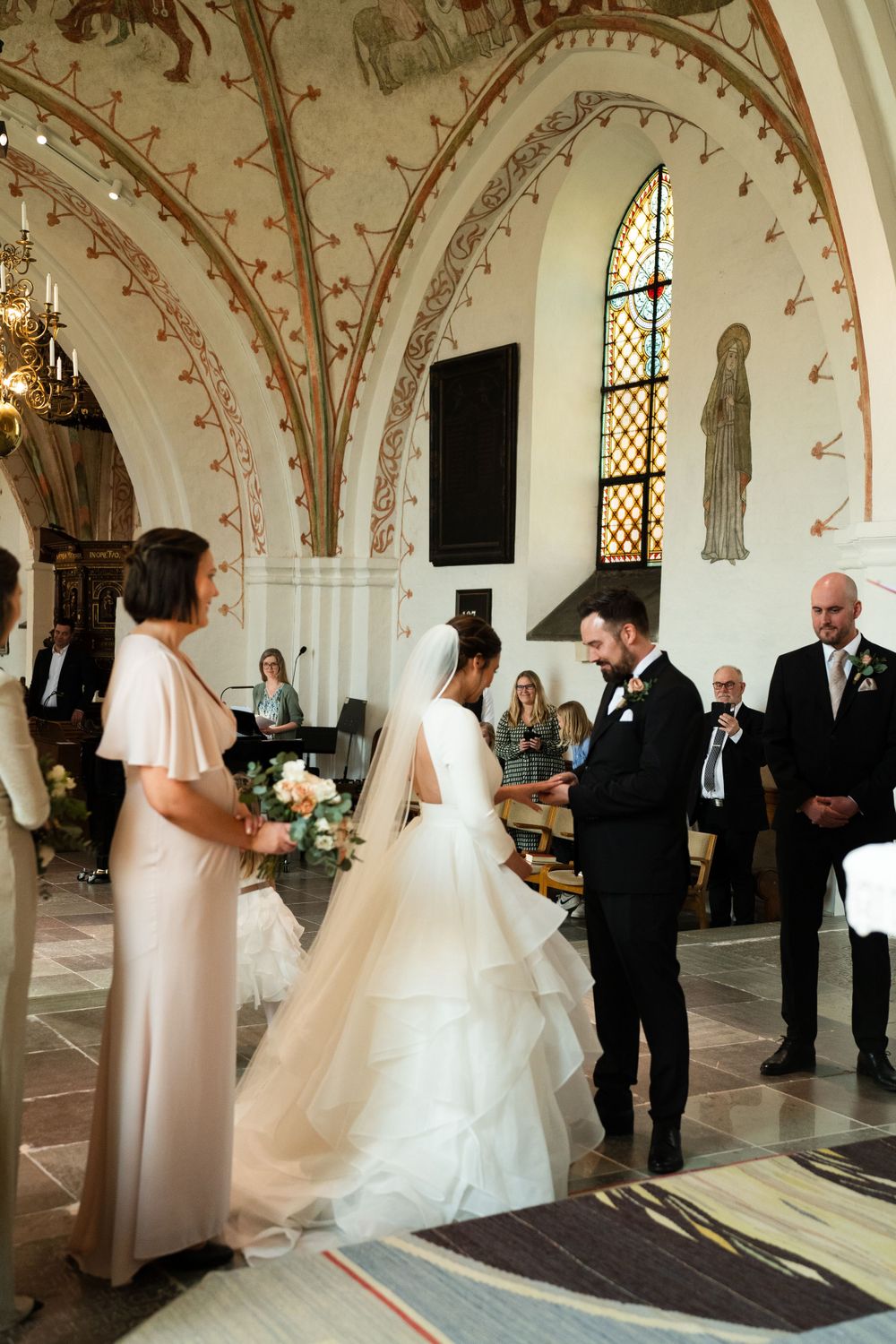 Wedding ceremony in historic church with vaulted ceilings and decorative wall paintings.