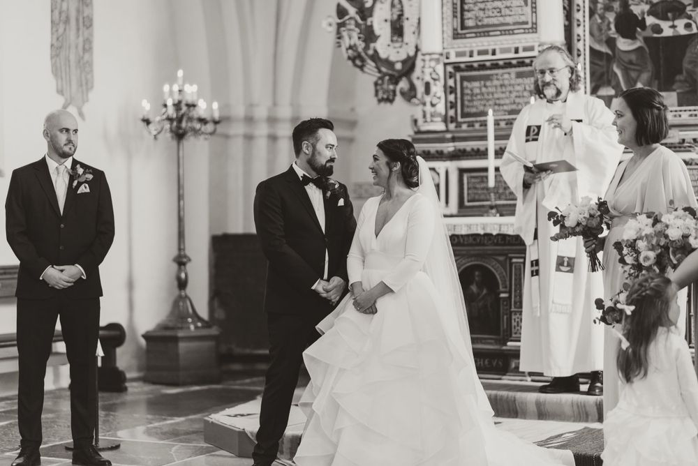 Black and white photo of wedding ceremony inside historic church with ornate decorations.
