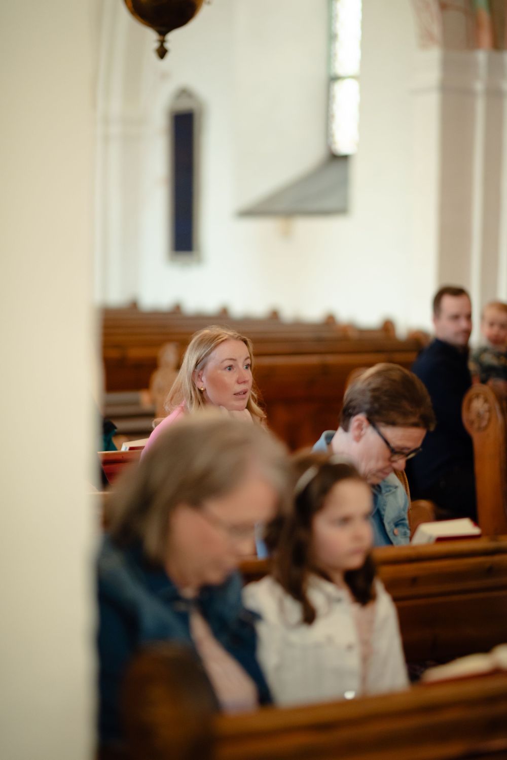 Wedding guests seated in traditional wooden church pews during ceremony.