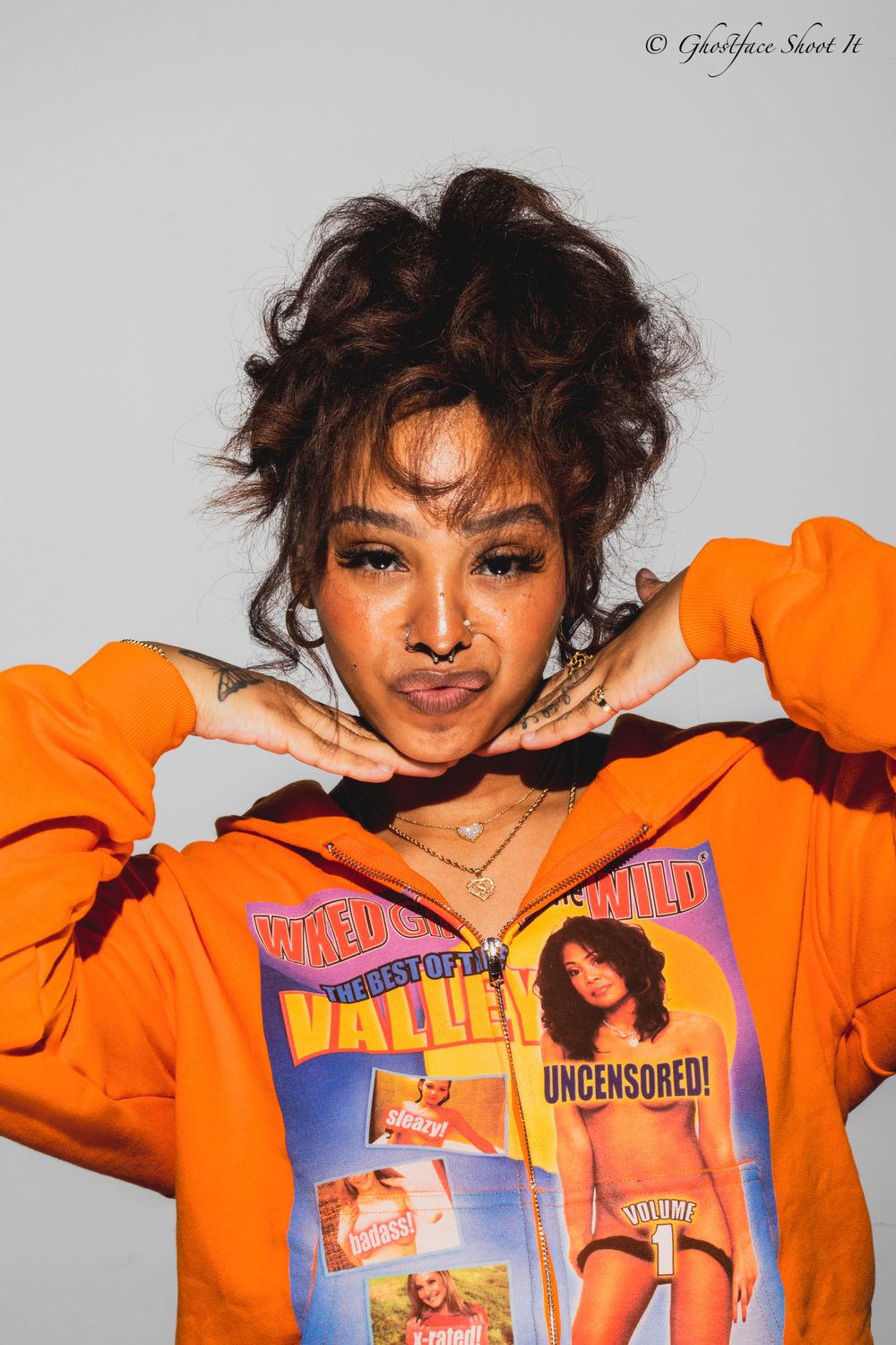 Studio portrait showing vibrant orange hoodie with vintage magazine cover print design.