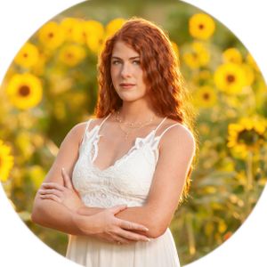 A person with red hair poses in a white dress against a vibrant backdrop of blooming sunflowers in golden sunlight. Red Models and Talent