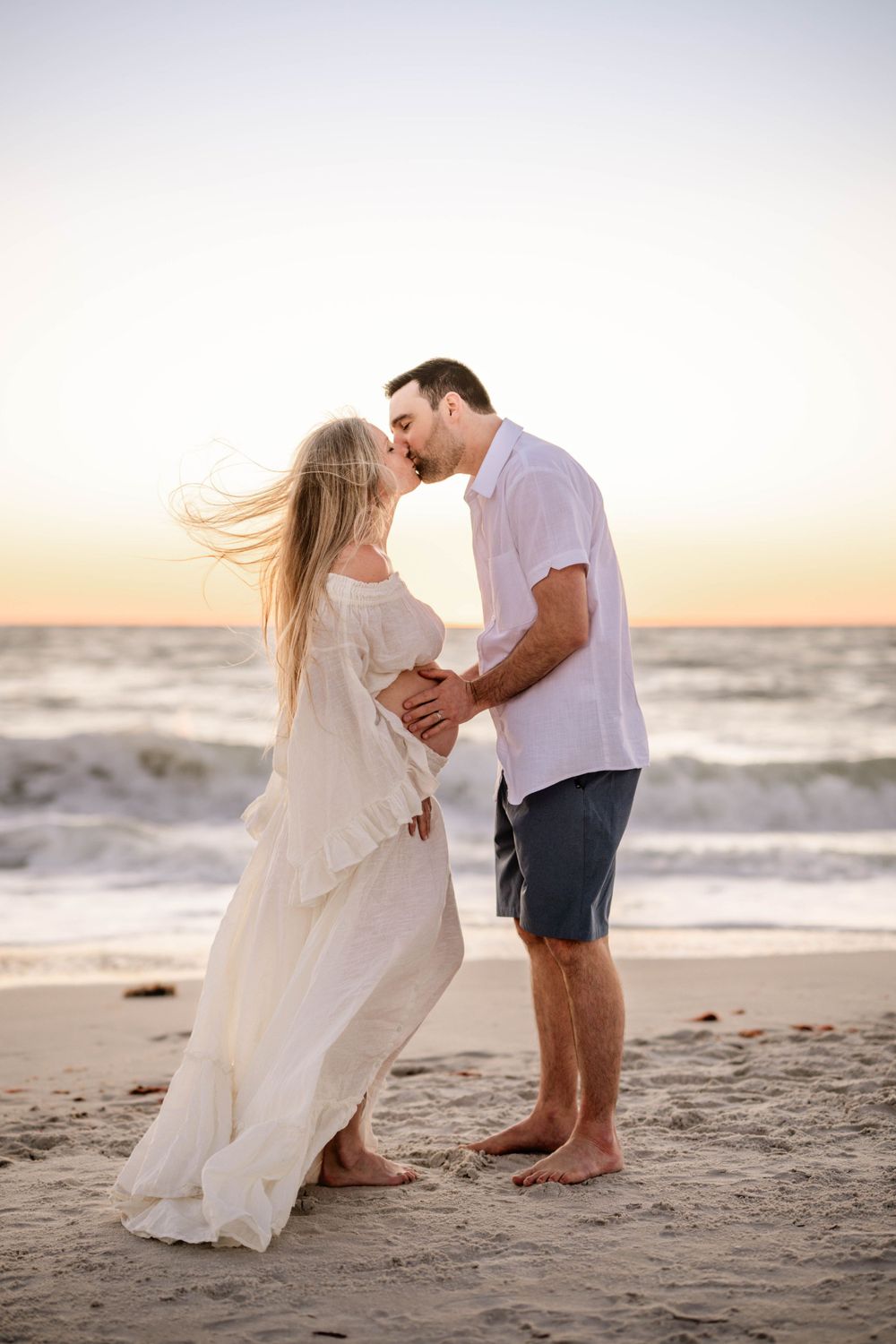 An intimate moment between a couple on the beach during golden hour.