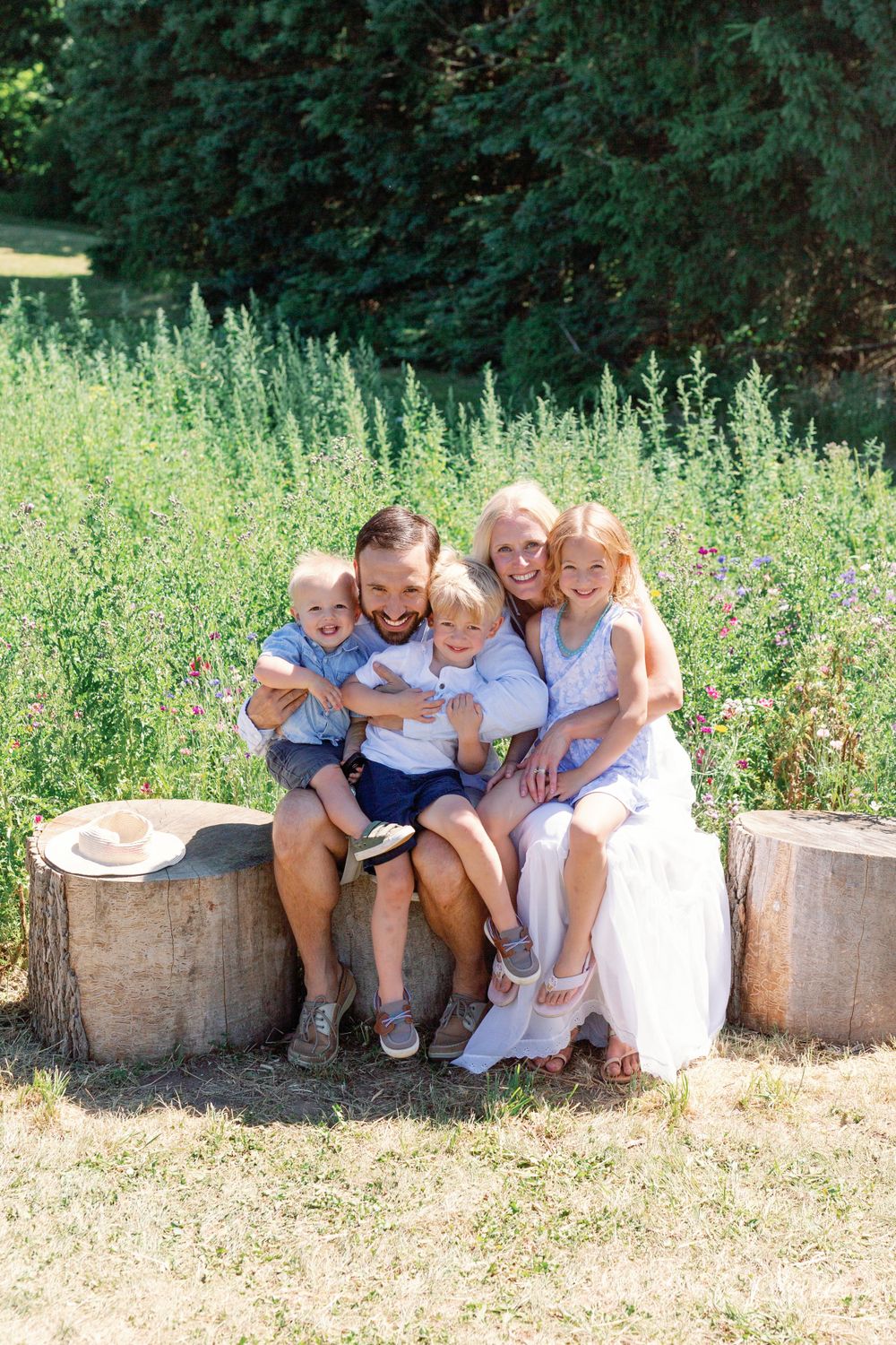 A group sitting together on wooden logs in a sunny outdoor setting.