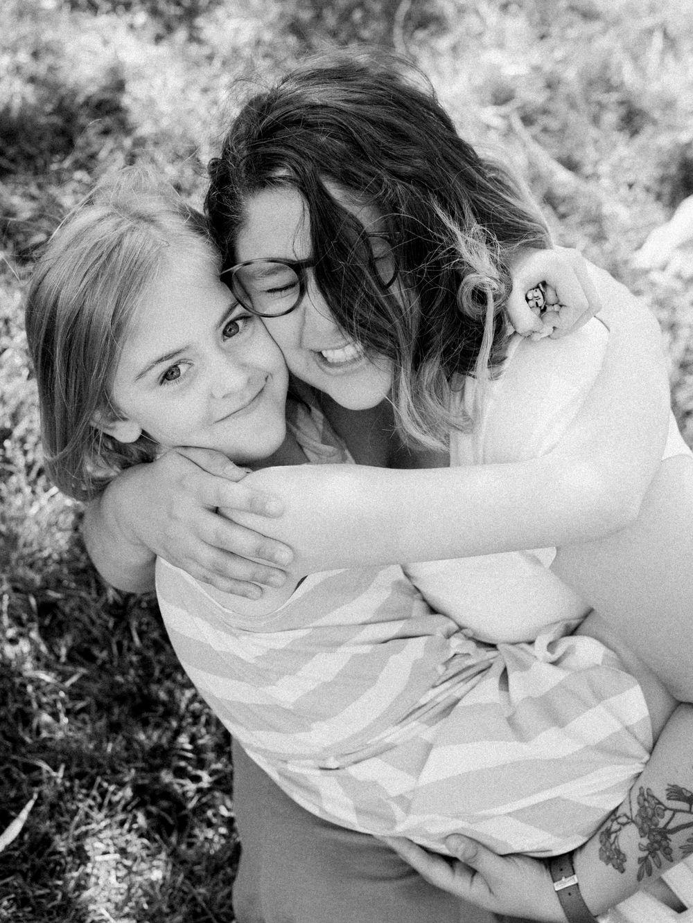 Black and white candid portrait of family sharing intimate moment outdoors.