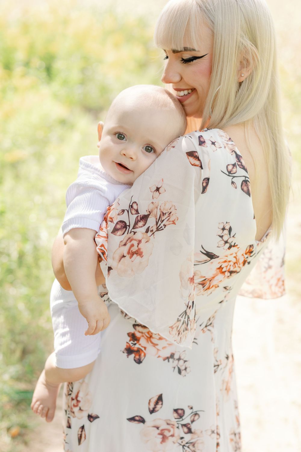 Parent and child sharing sweet moments in a sunlit meadow wearing floral prints.