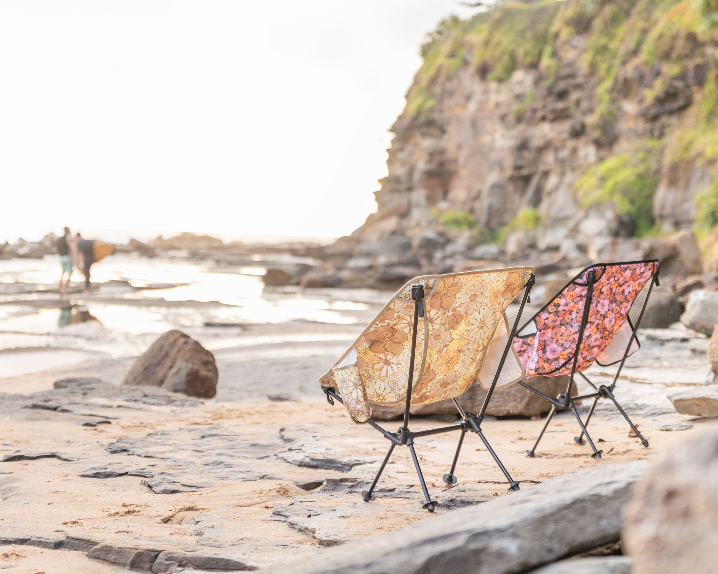 Portable folding chairs set up among rocky coastal terrain. Campout Co Camping Chairs Product Photography.