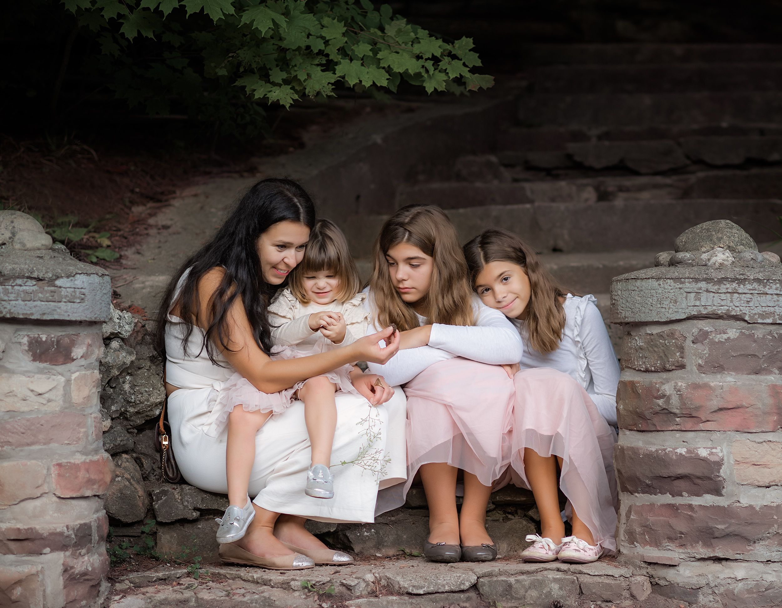 a mother with three daughters  are sitting on the stairs at Belfountain conservation area  and being photographed