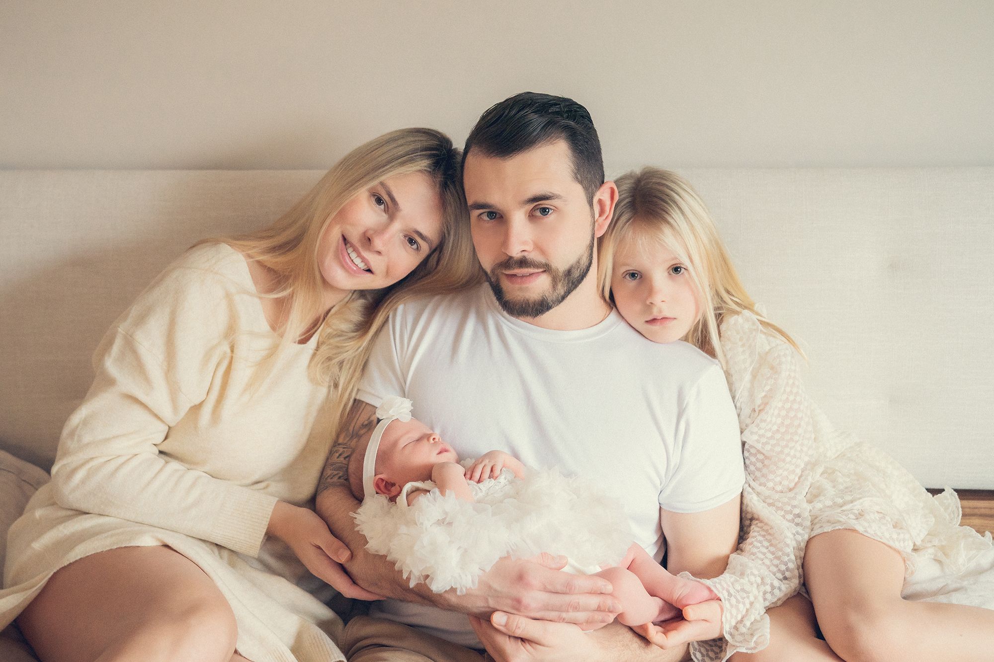 family with the newborn baby are posing for a session on the bed at home in Vaughan, Ontario