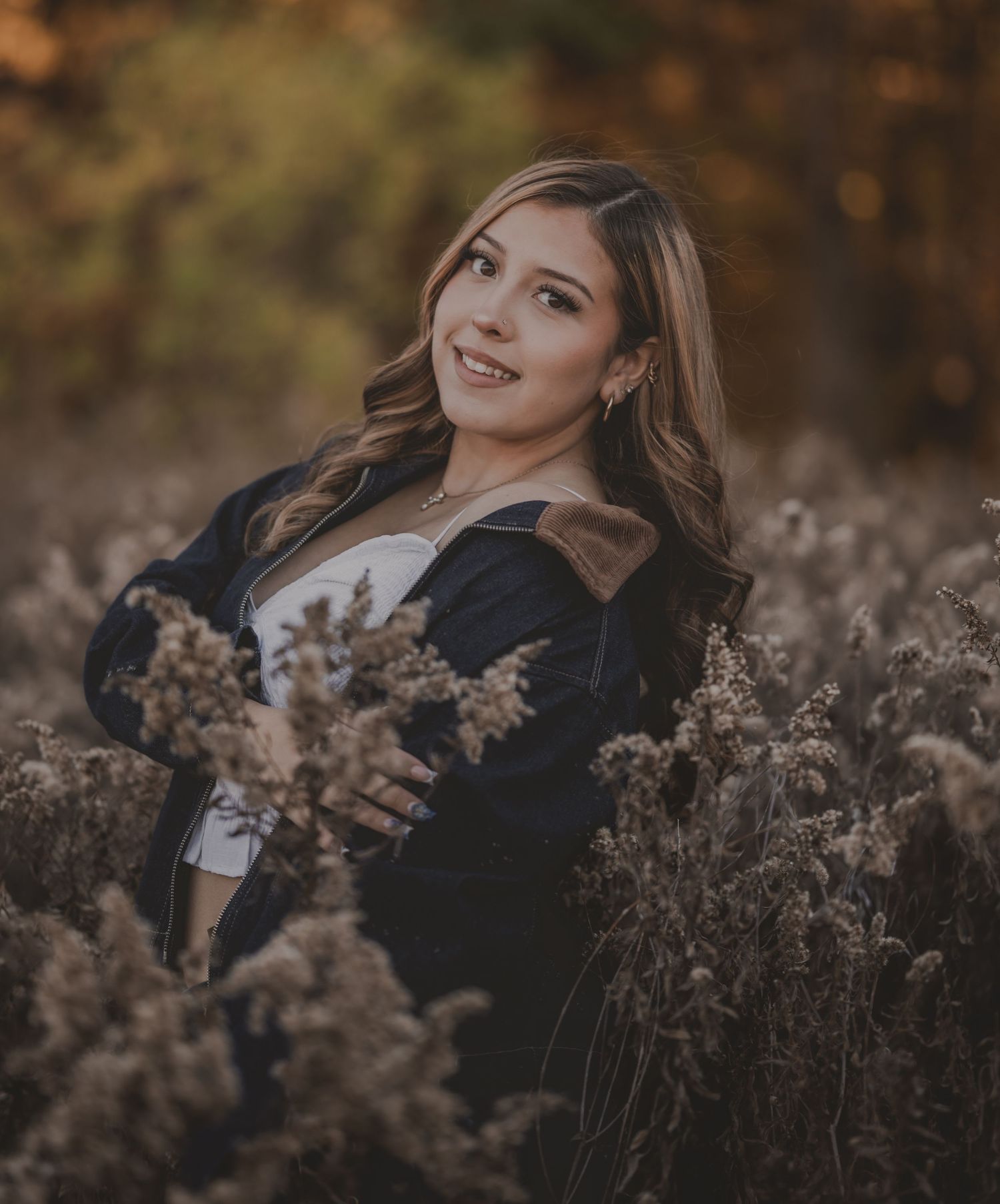 Graduate in cap and gown sitting on stone steps near wooden door and brick wall.