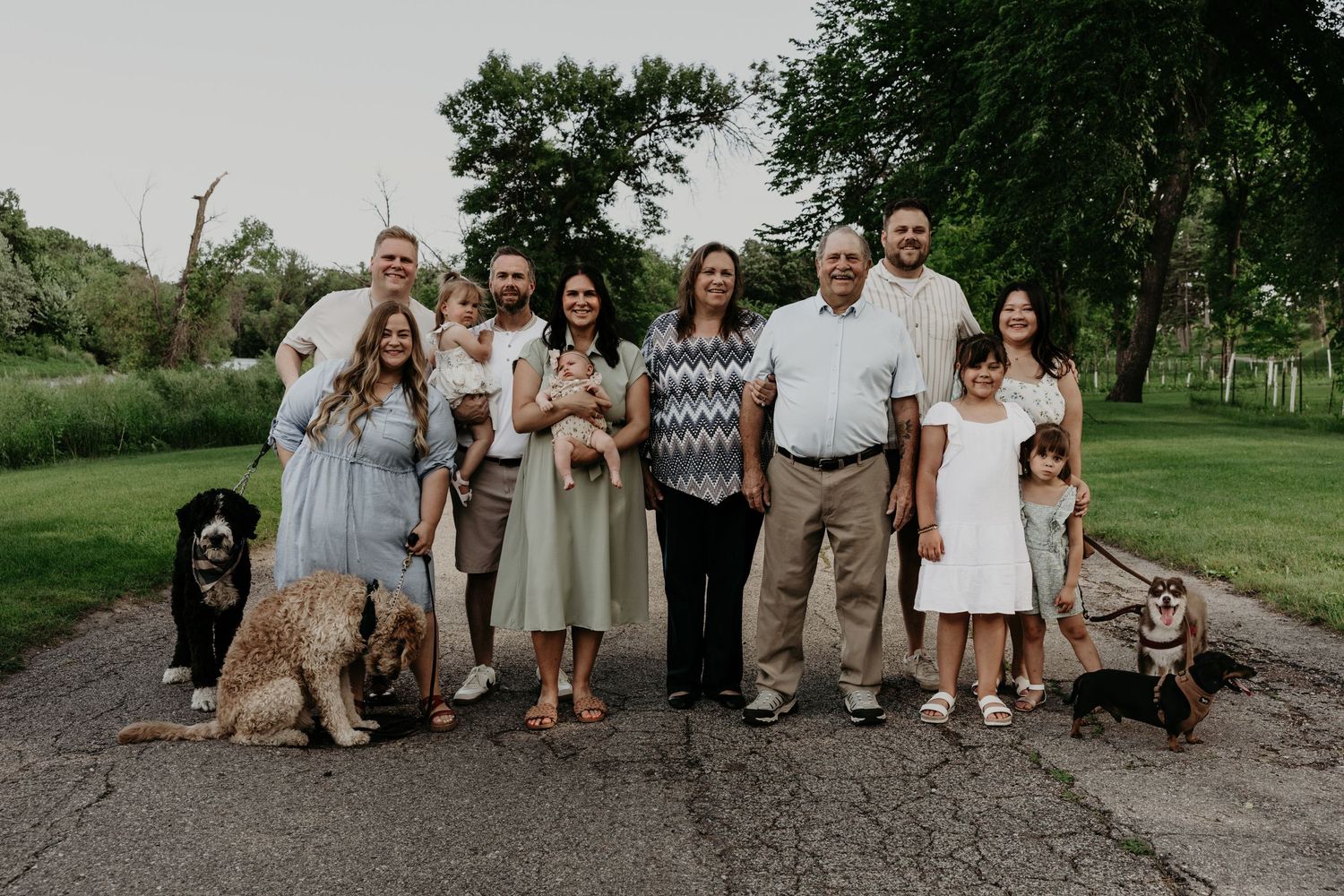 A casual family portrait session outdoors with coordinated neutral-colored outfits.