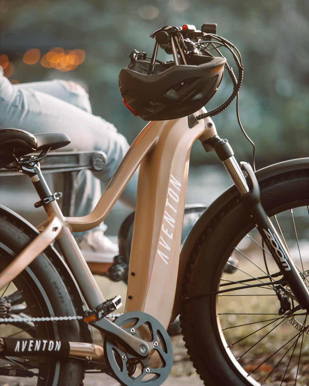 Close-up of a tan-colored Aventon electric bike's front handlebars and helmet.