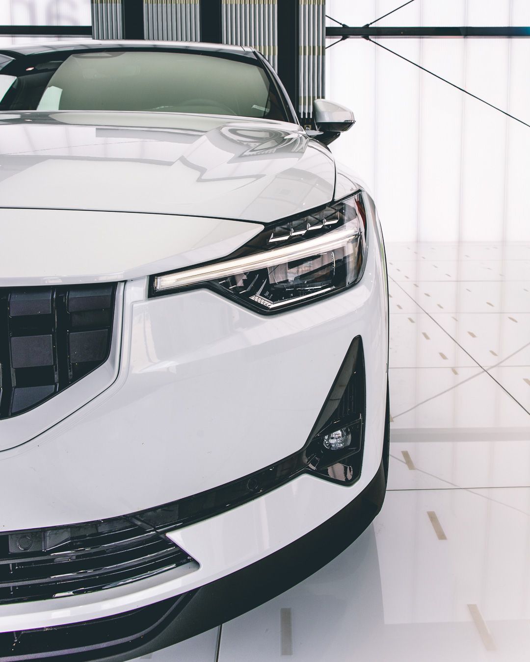 Close-up of white luxury car headlight and front quarter panel design.