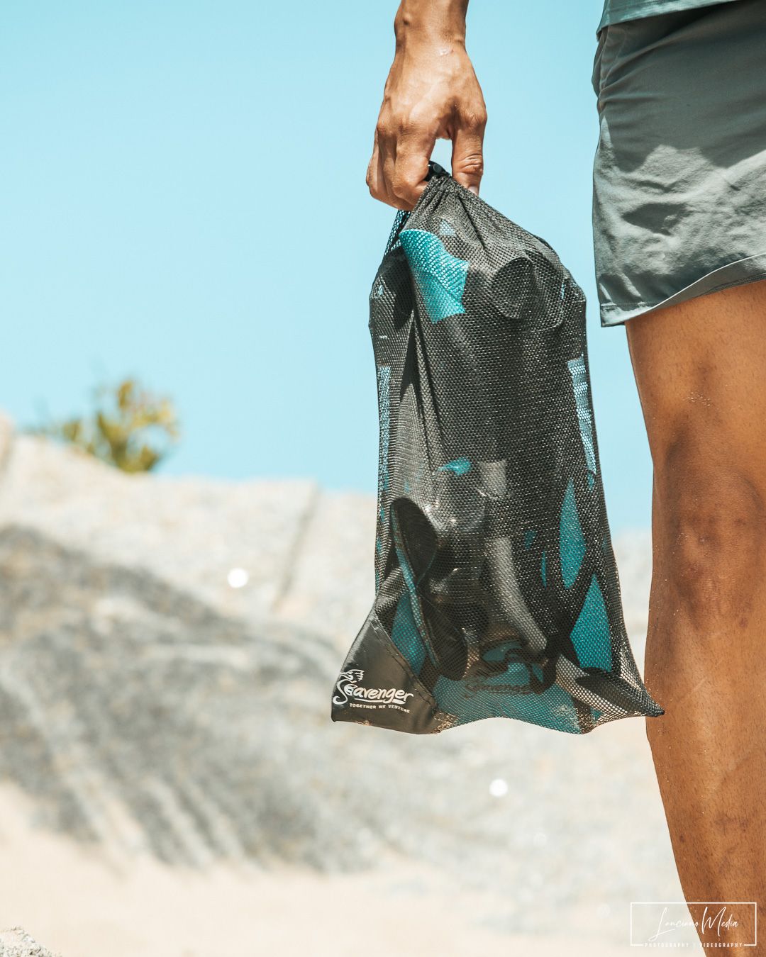 Hand holding a waterproof bag against blue sky background.