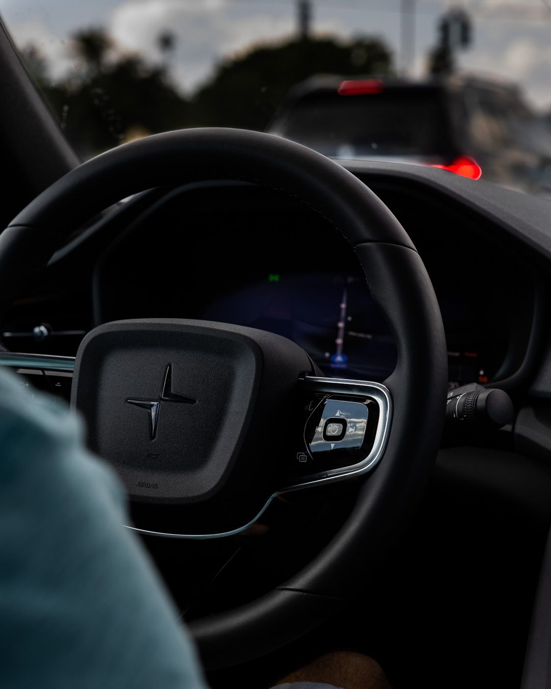 Modern car steering wheel with digital display and Polestar logo against a dusky background.