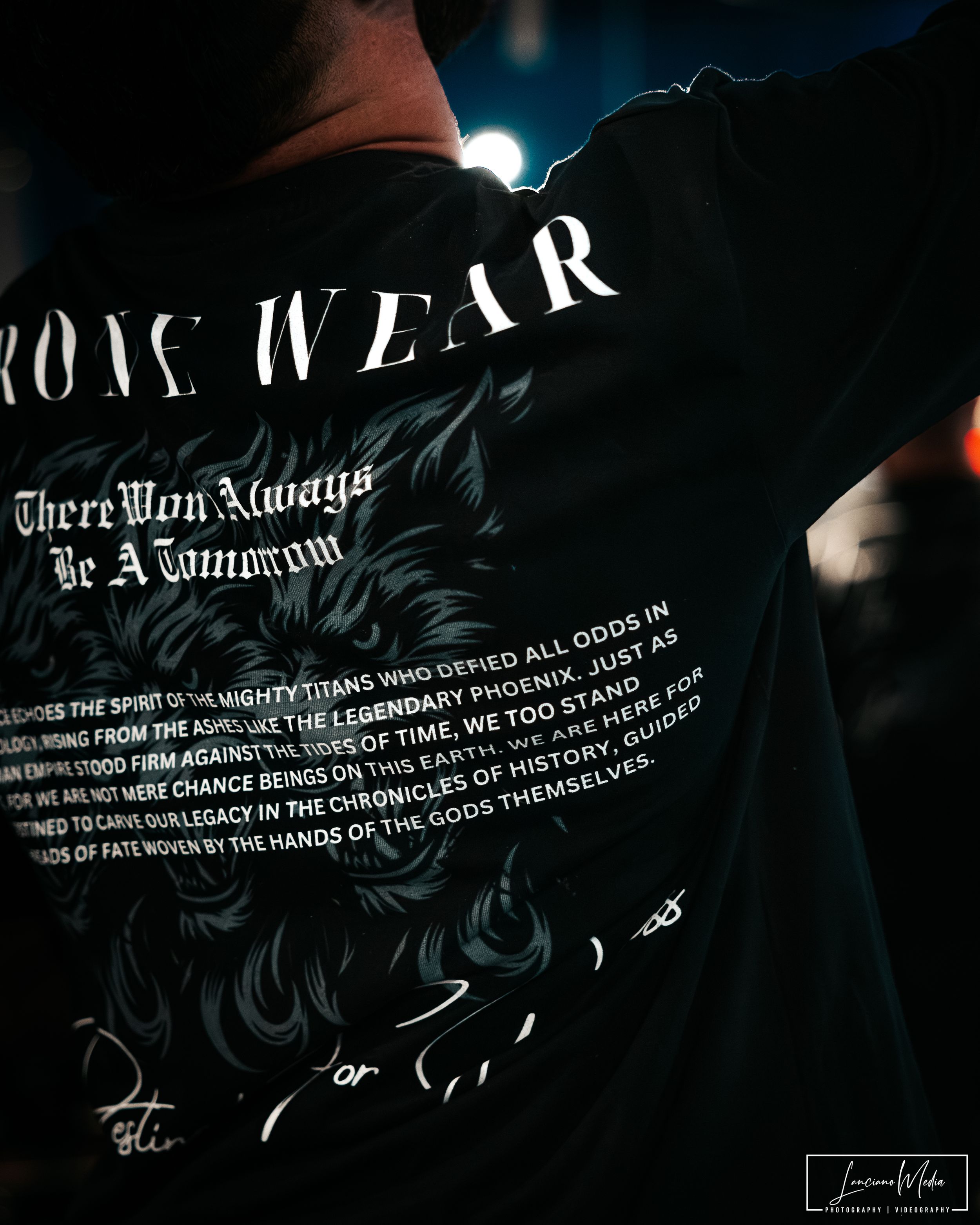 Close-up of black streetwear clothing with gothic text design and ornate graphics.