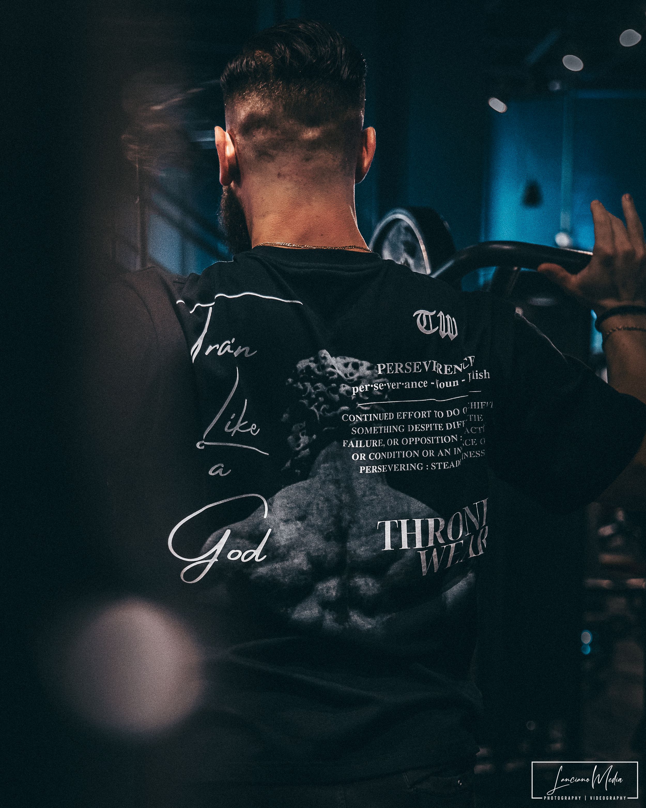 Back view of dark streetwear clothing with text and signature designs in low light.