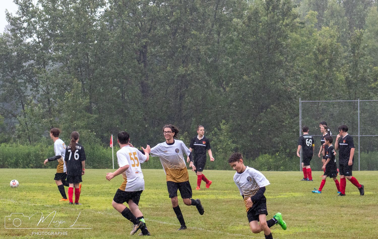 Soccer match action on green field with players in white and black uniforms.