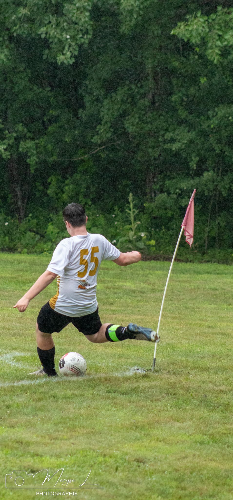 Soccer player preparing to take a corner kick on grassy field with corner flag.