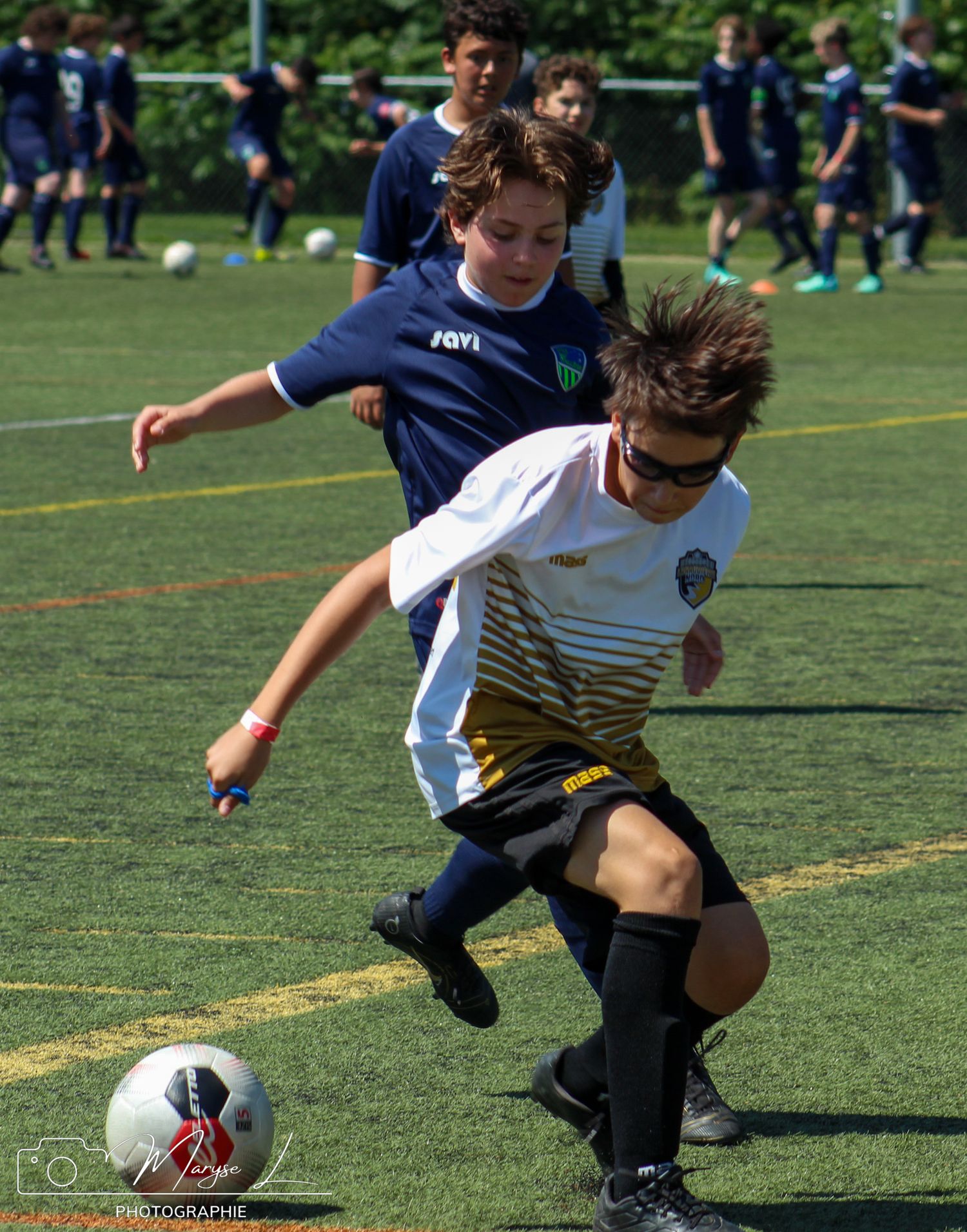 Competitive soccer match shows players fighting for ball control on green turf field.