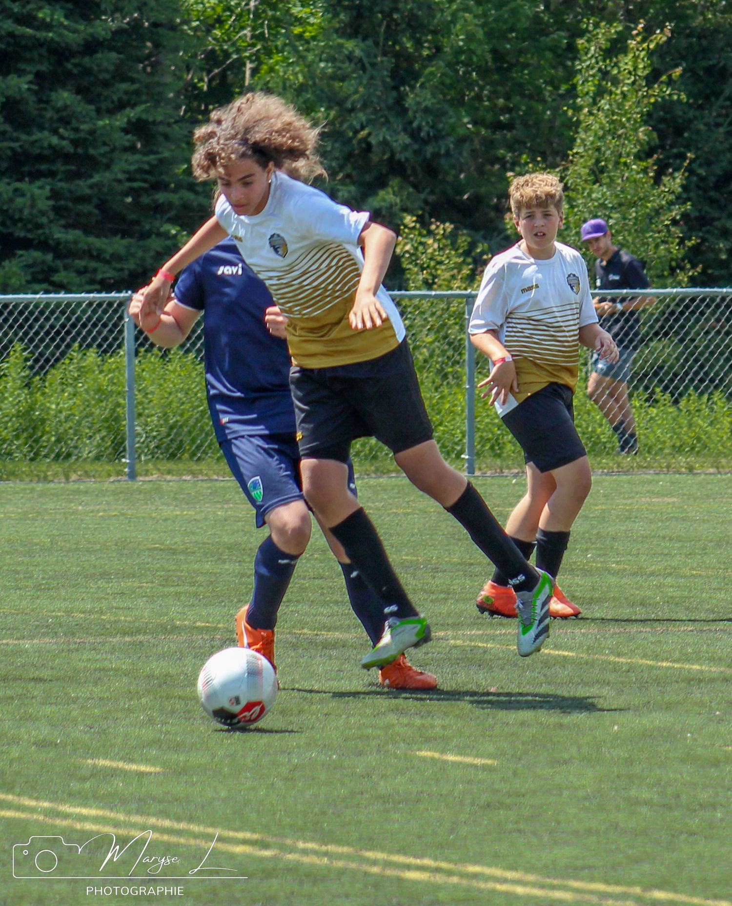 Soccer players compete for possession of the ball during an intense youth match on a sunny day.