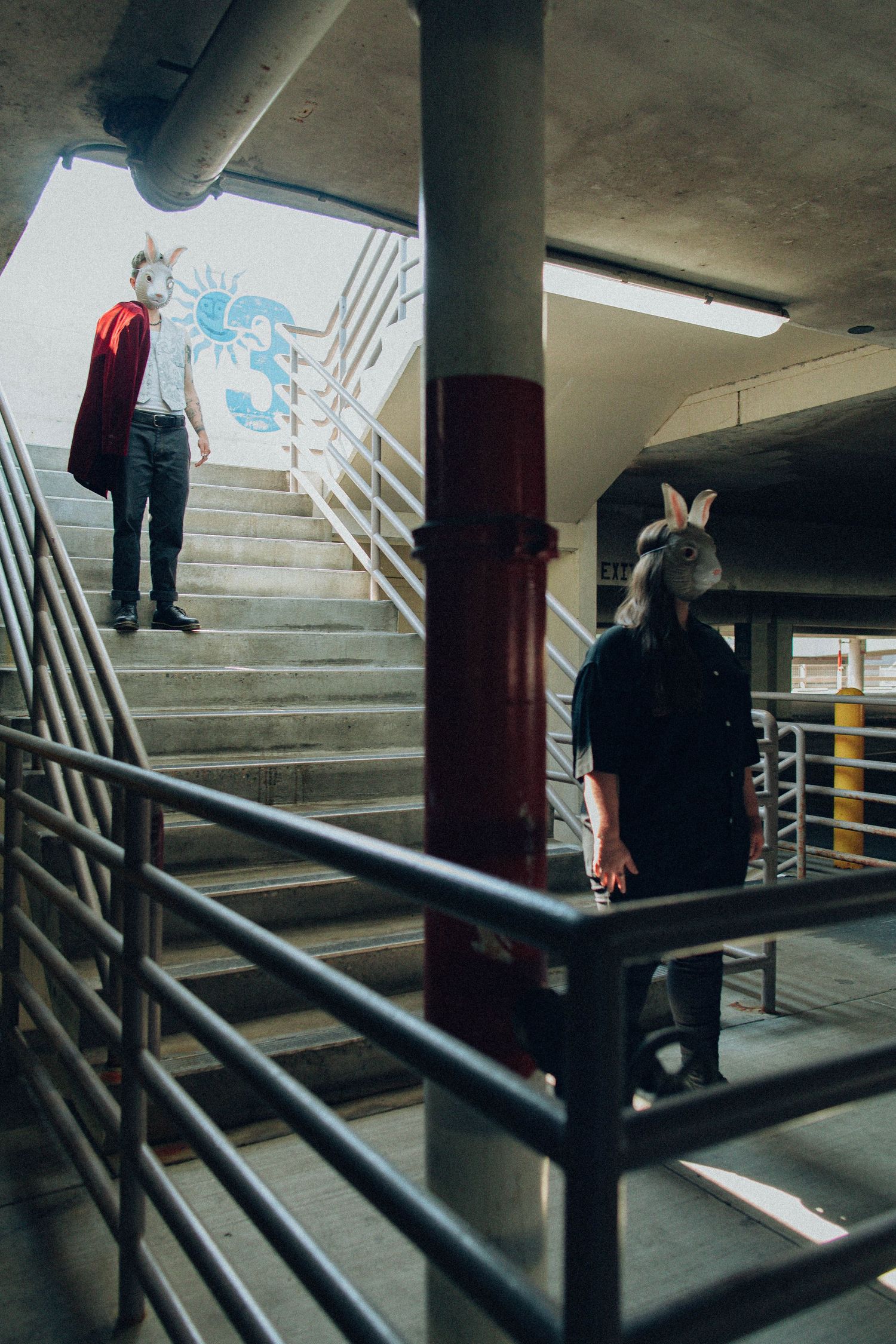 graphic and cinematic photograph of two models as rabbit characters, stark lighting, parking garage location.