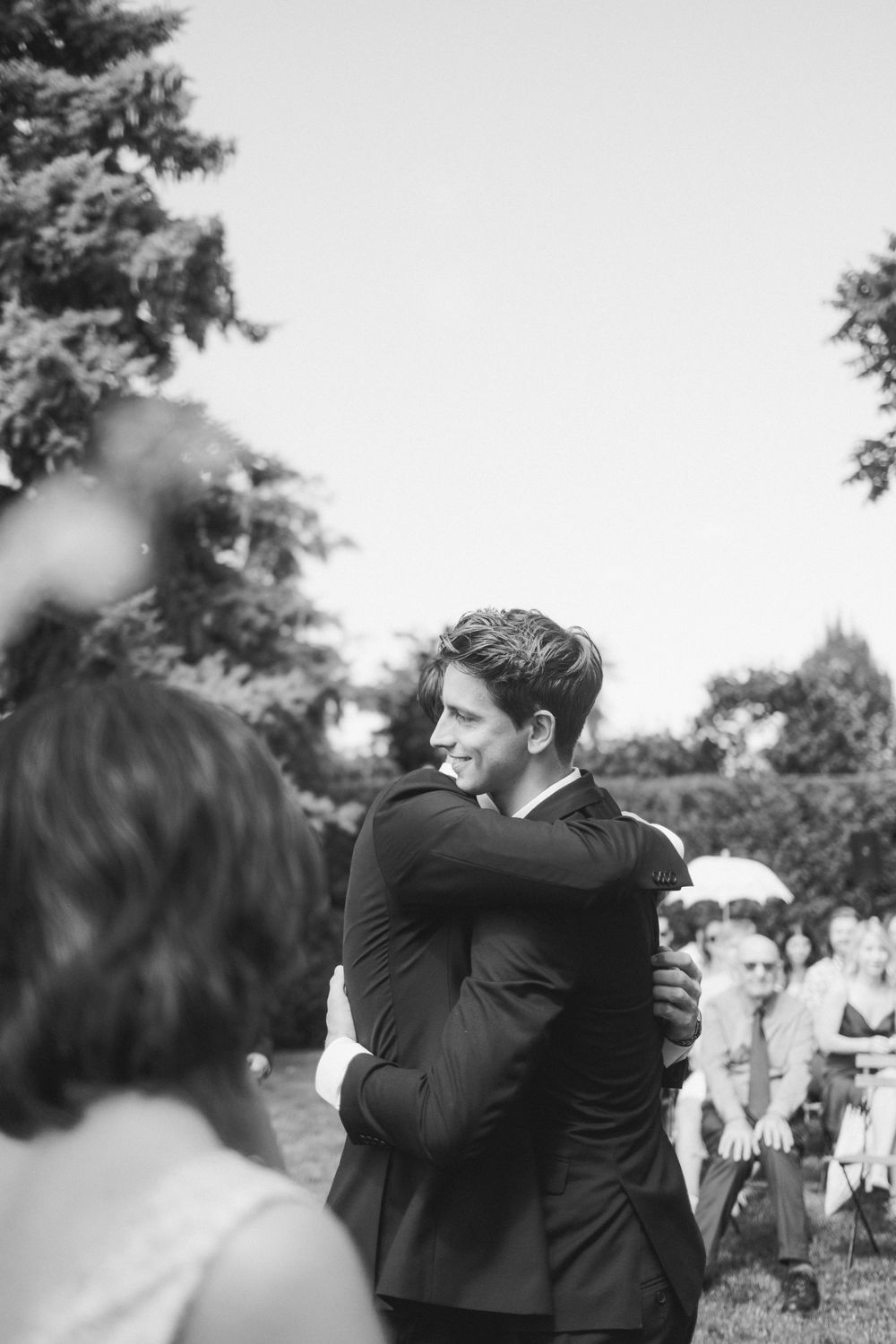 An emotional embrace during a backyard wedding ceremony captured in black and white.