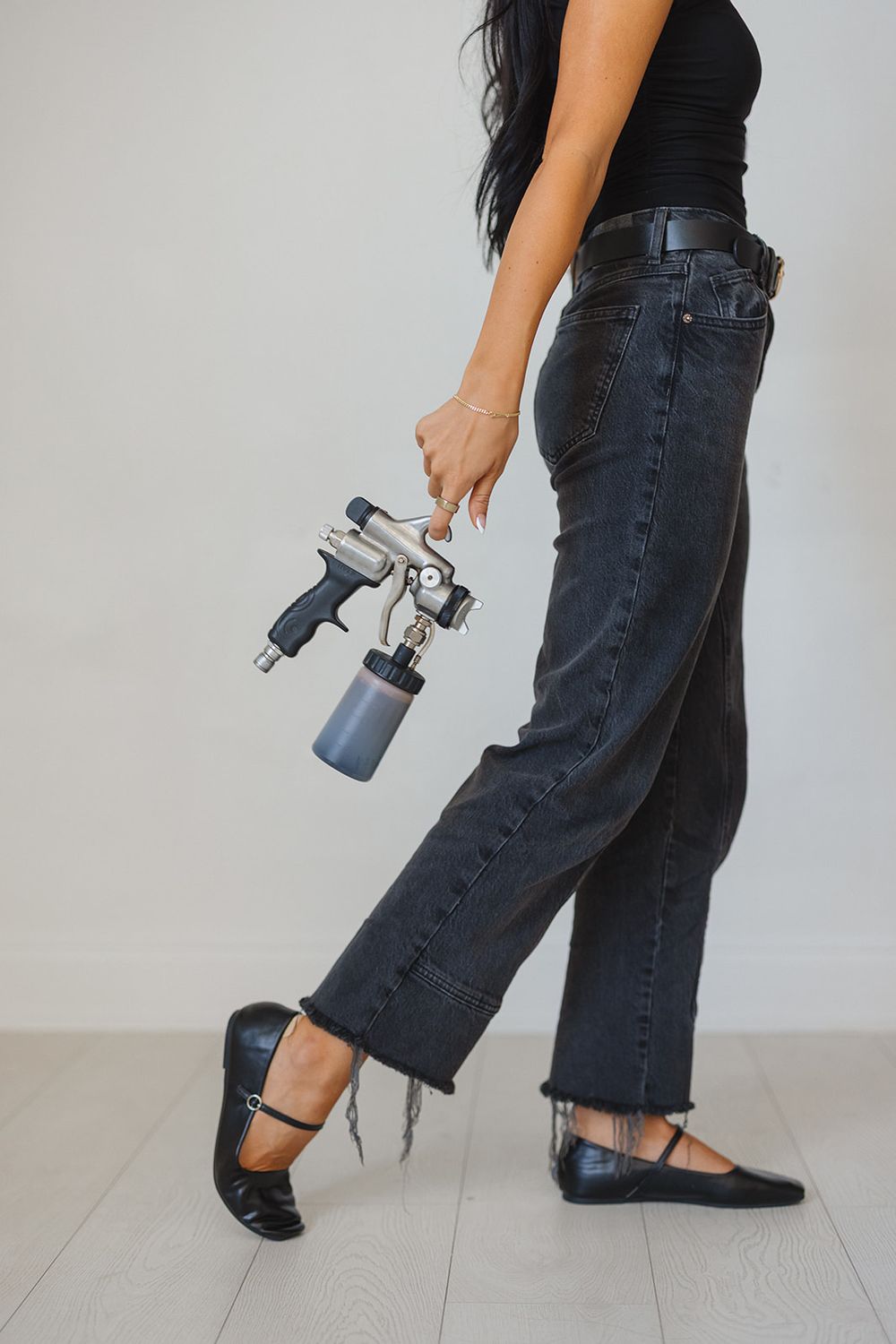 Person in distressed black jeans using a spray bottle on their denim to create DIY distressed details.