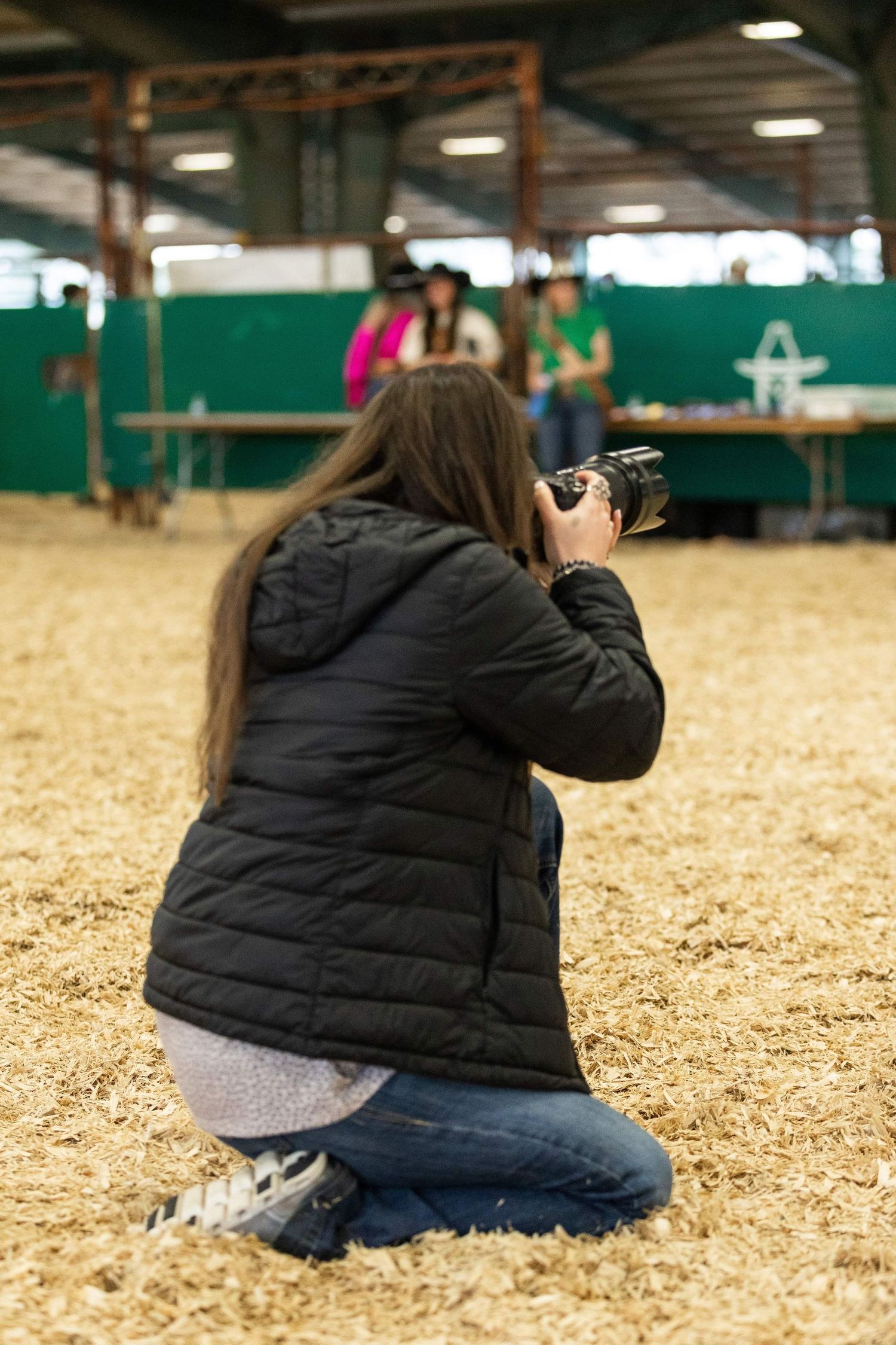 Photographer crouching low to capture shots on wood chip covered ground.