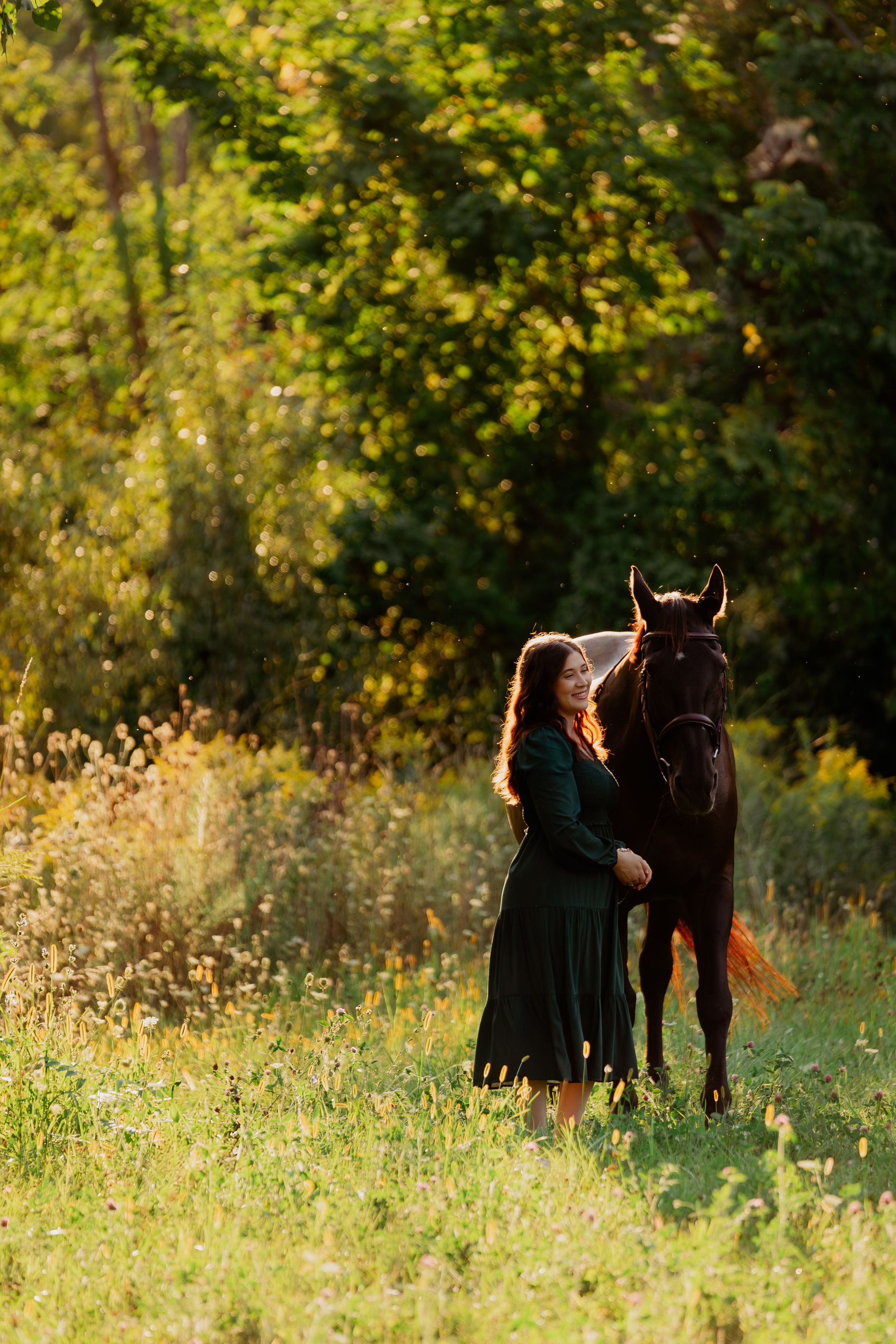 A horse and companion share a tender moment in a sunlit meadow surrounded by autumn foliage.
