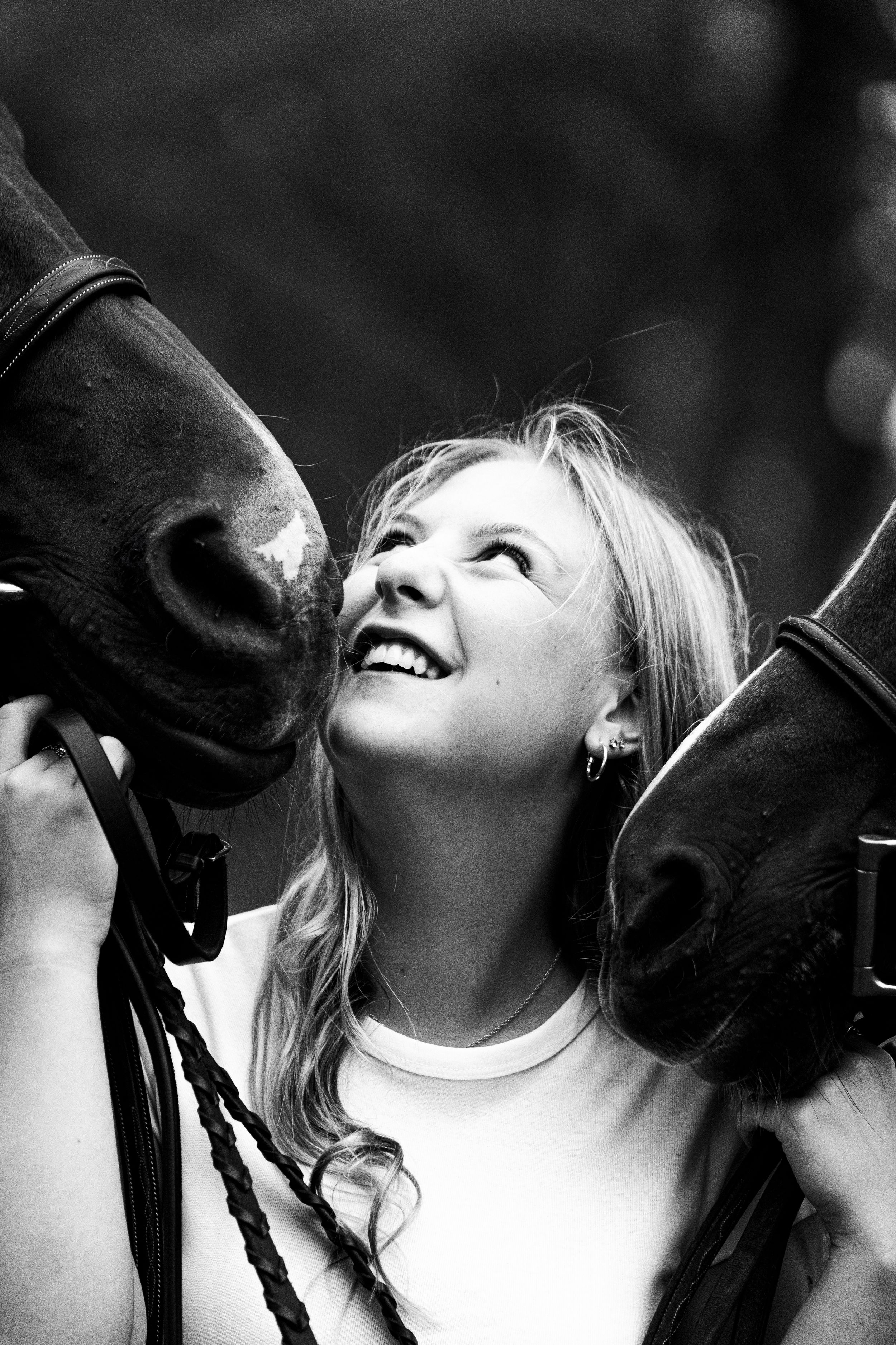 A joyful black and white moment shared between a person and two horses.