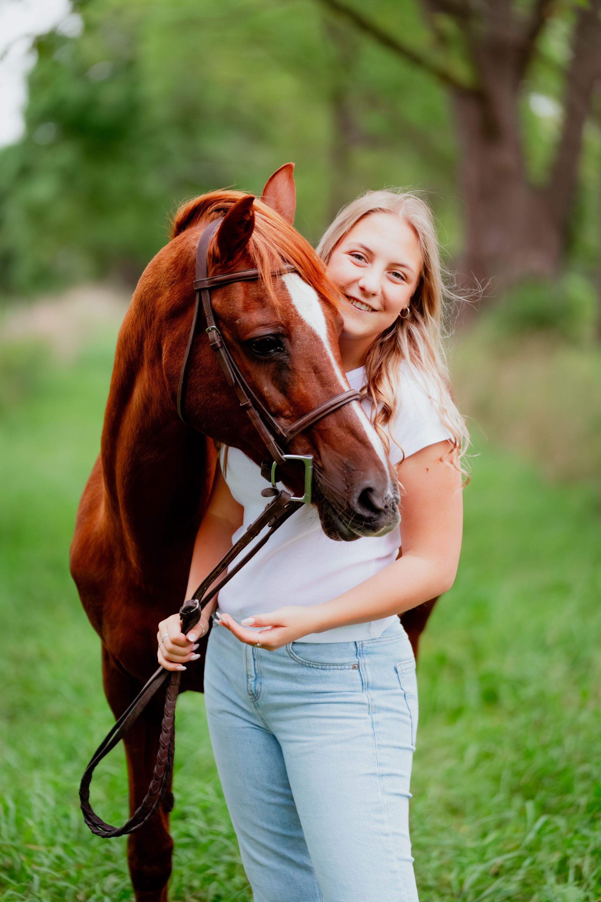 A casual portrait with a chestnut horse against a green natural background.