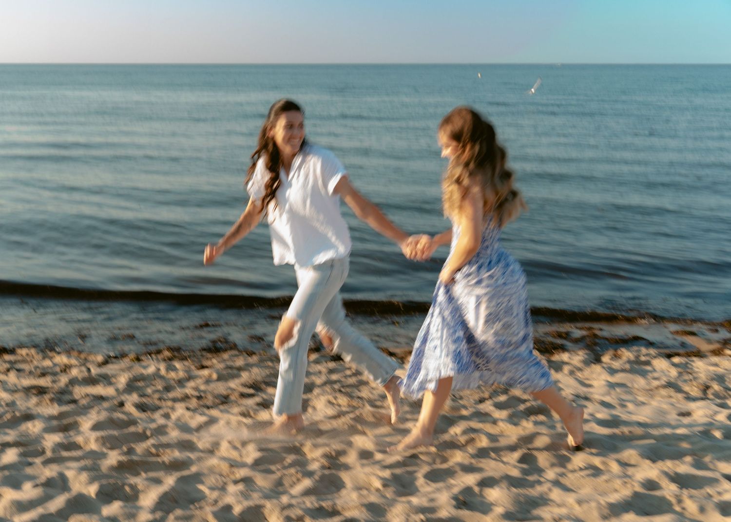 Timeless black and white photograph of two girls running along ocean edge, carefree and playful.