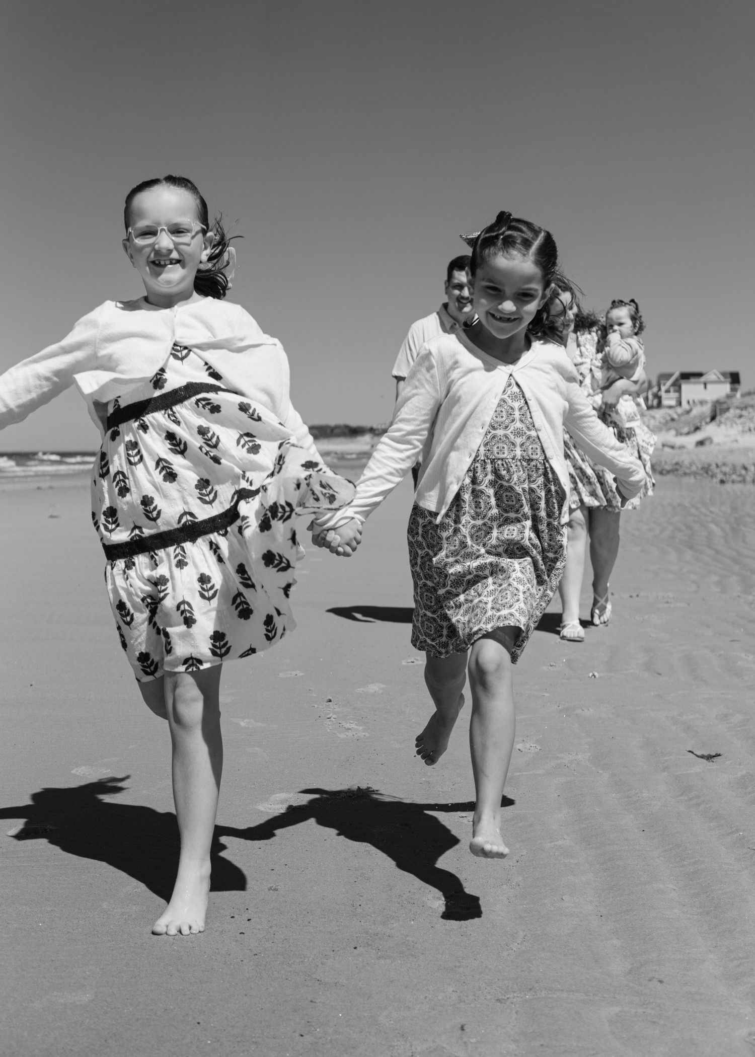 Timeless black and white photograph of two girls running along ocean edge, carefree and playful.